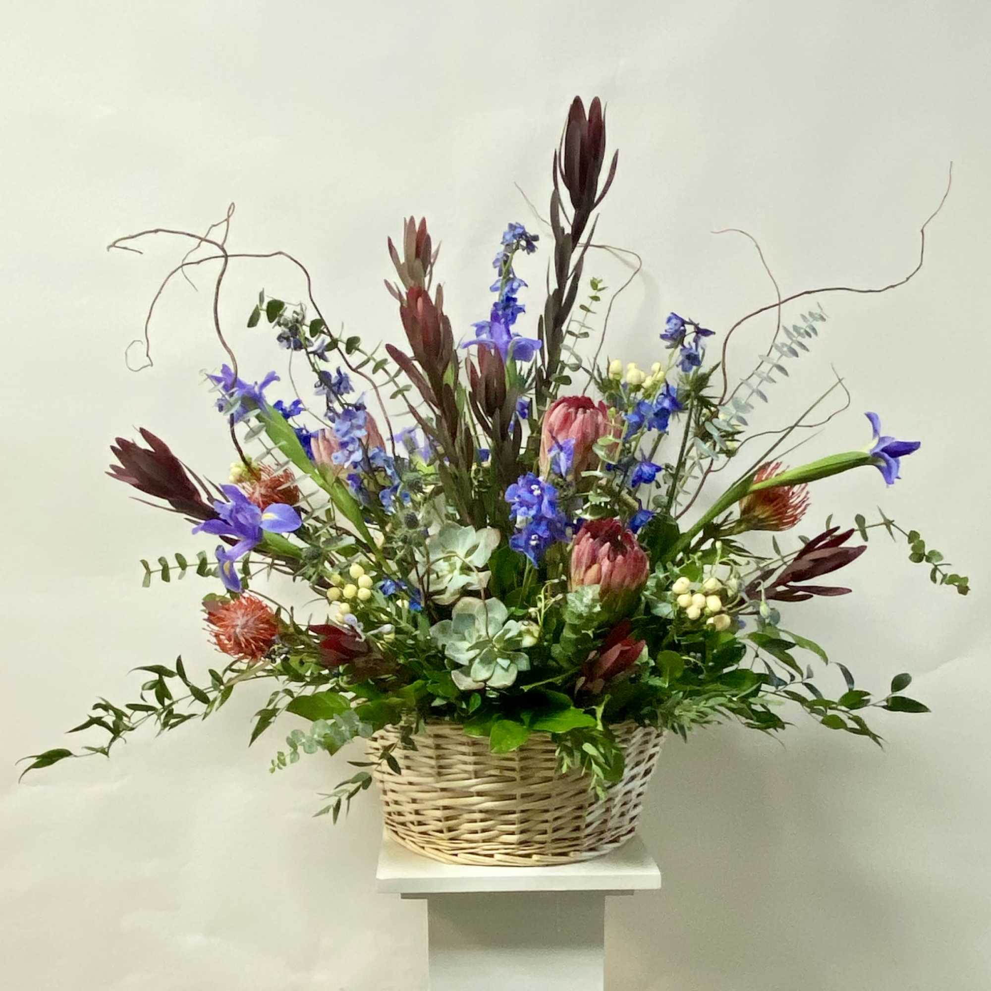 Tall mixed flower arrangement in a wicker basket