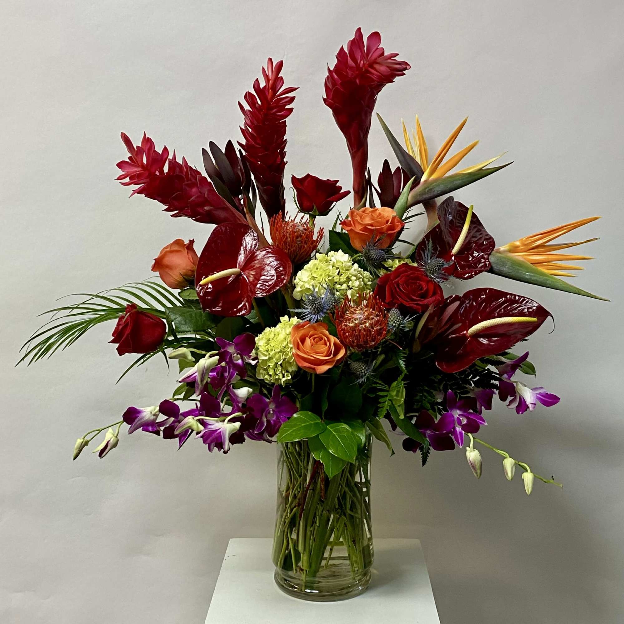 Tropical bouquet with red and orange flowers in a clear glass vase
