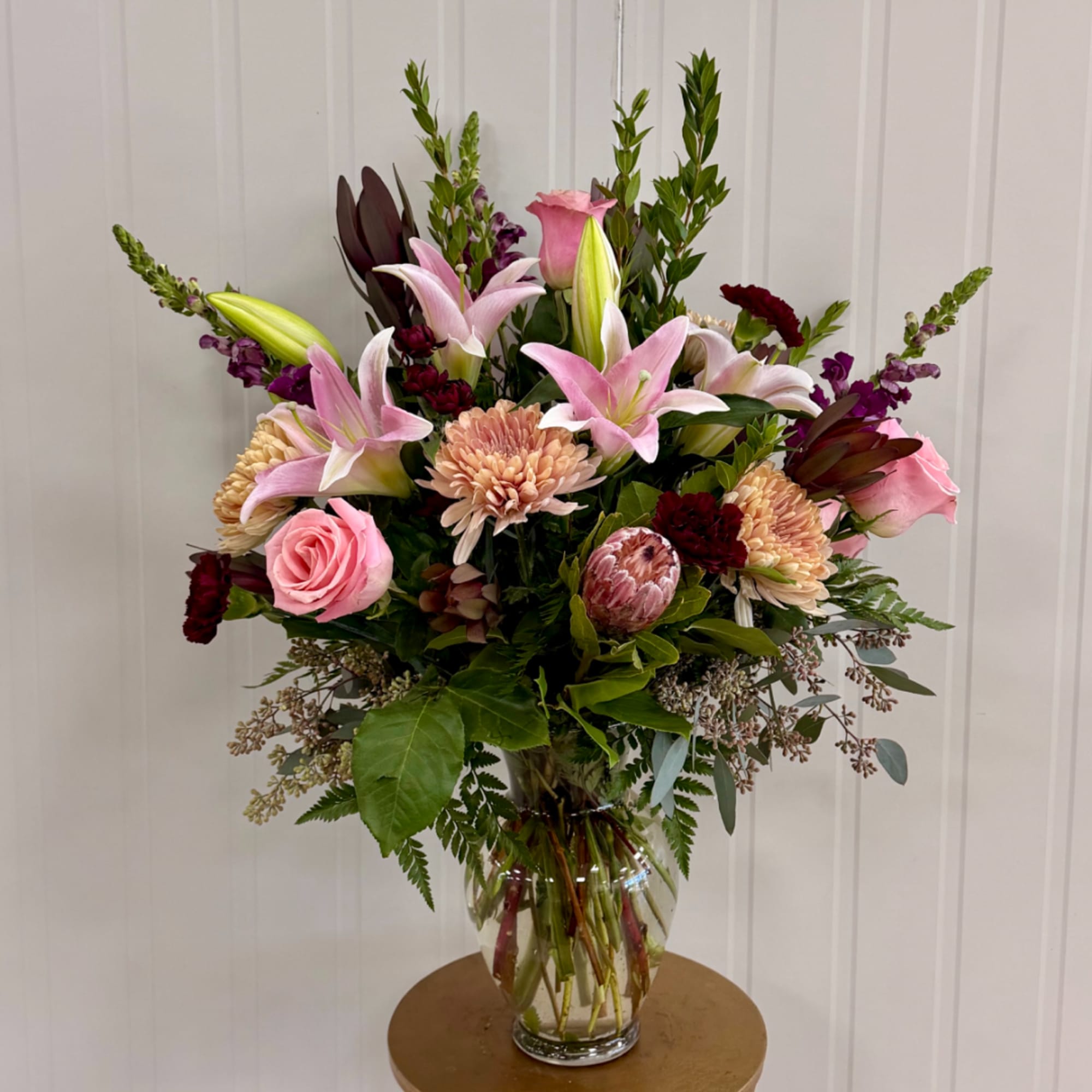 Mixed bouquet of pink lilies, roses, and chrysanthemums in a clear glass vase