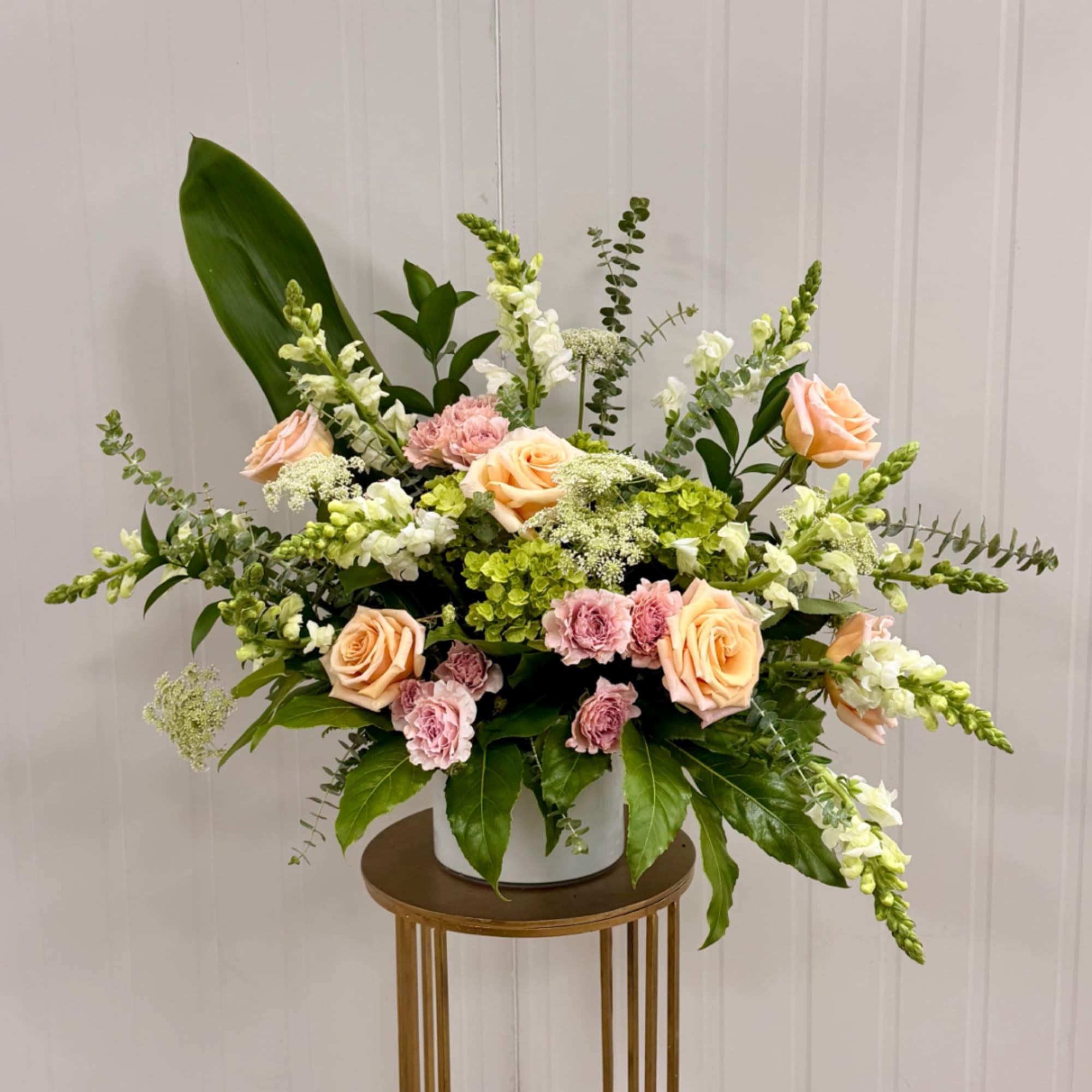 Peach roses and pink carnations in a white vase with tall white blooms