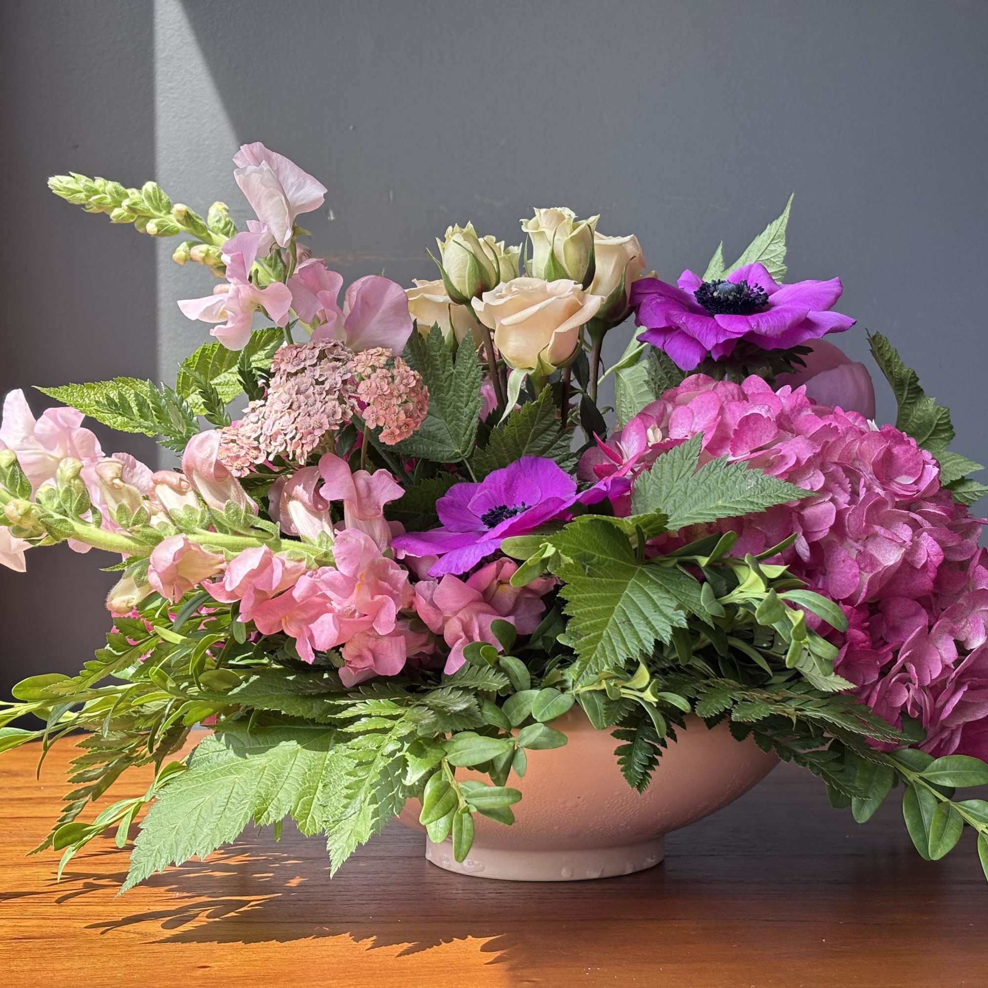Pink and purple floral arrangement in a low bowl vase