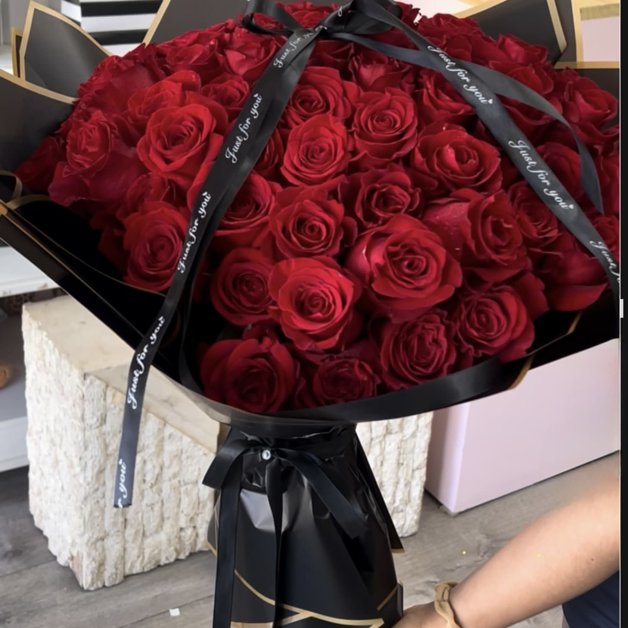 Large bouquet of red roses wrapped in black paper with a black ribbon