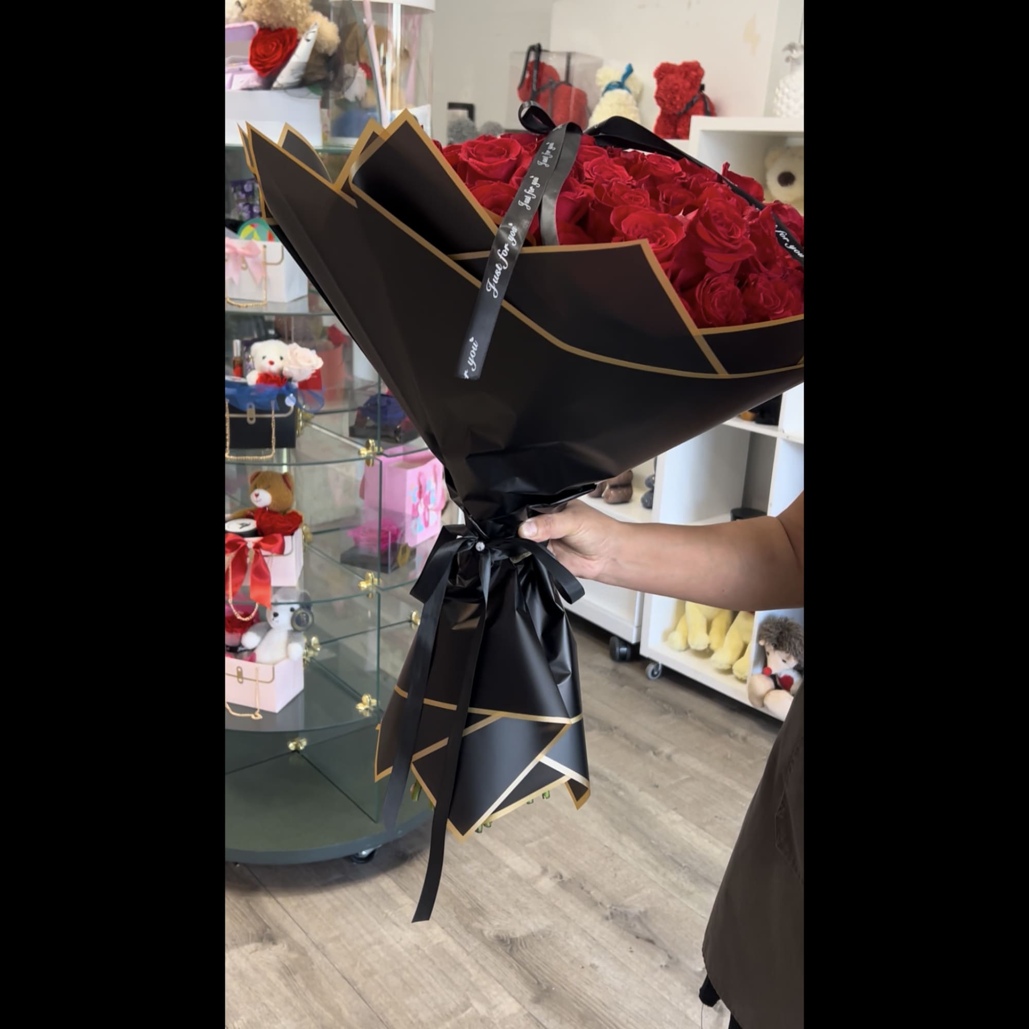 Large bouquet of red roses wrapped in black paper with gold trim