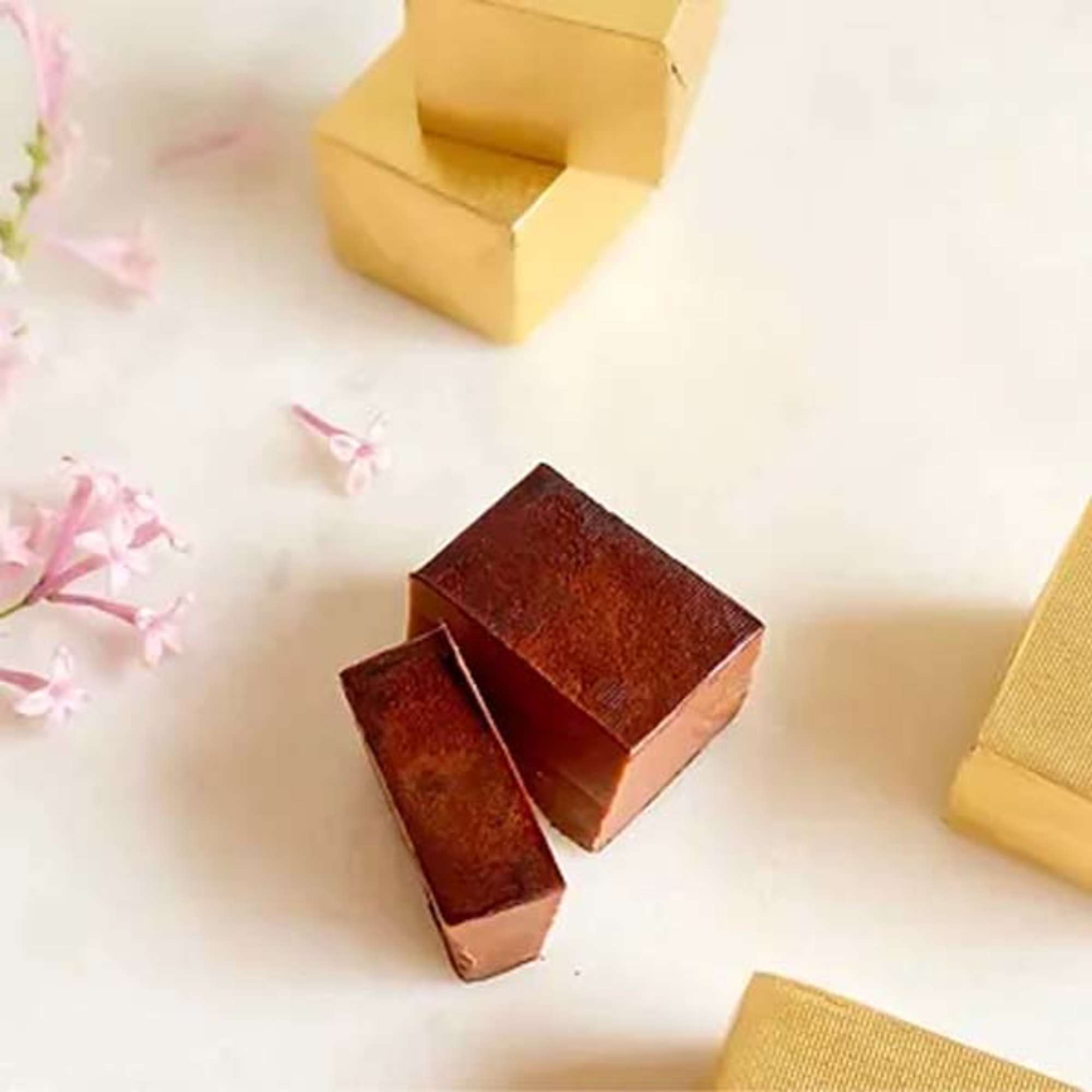 Open gift boxes on a white surface with pink blossoms nearby