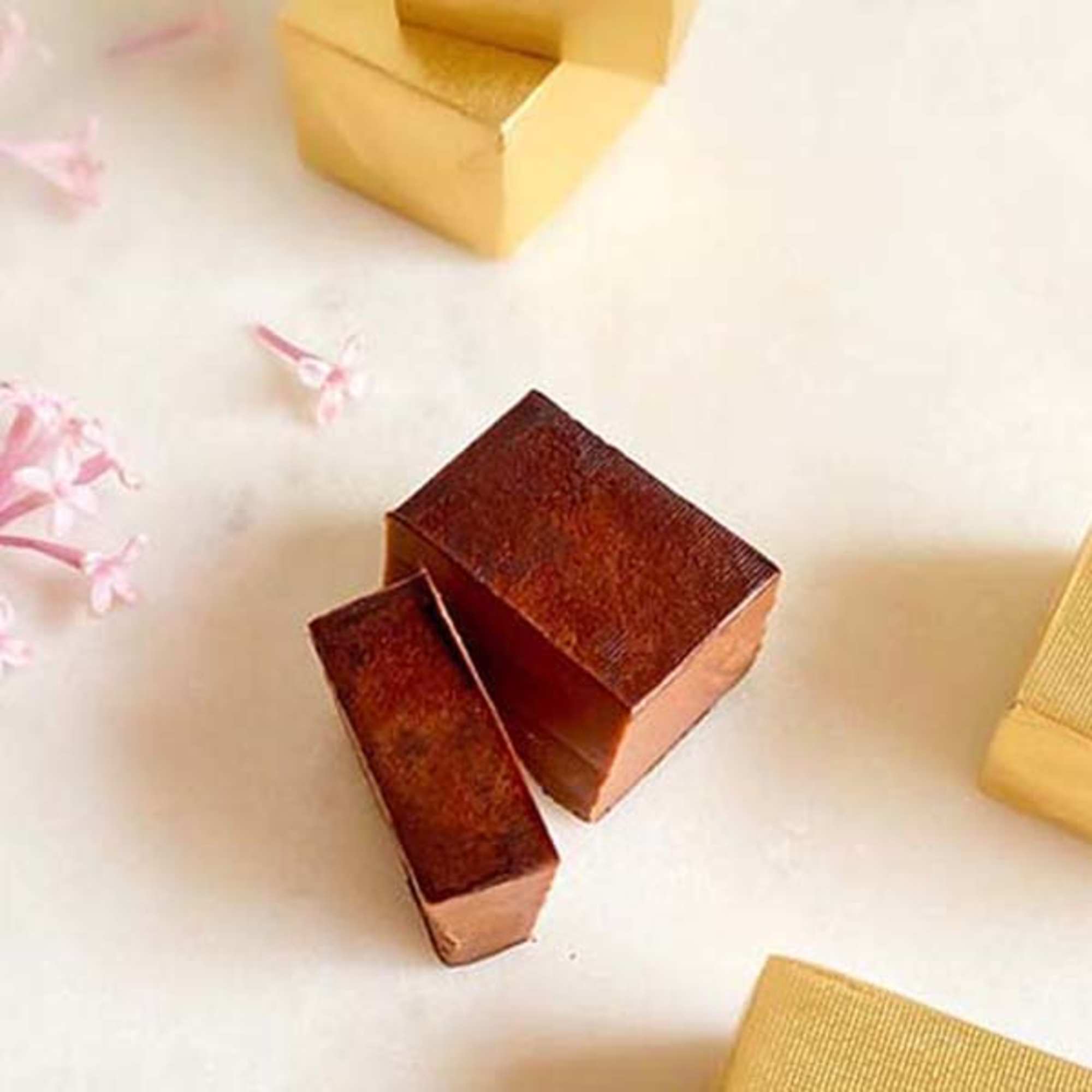 Small metallic gift boxes on a white surface with pink petals
