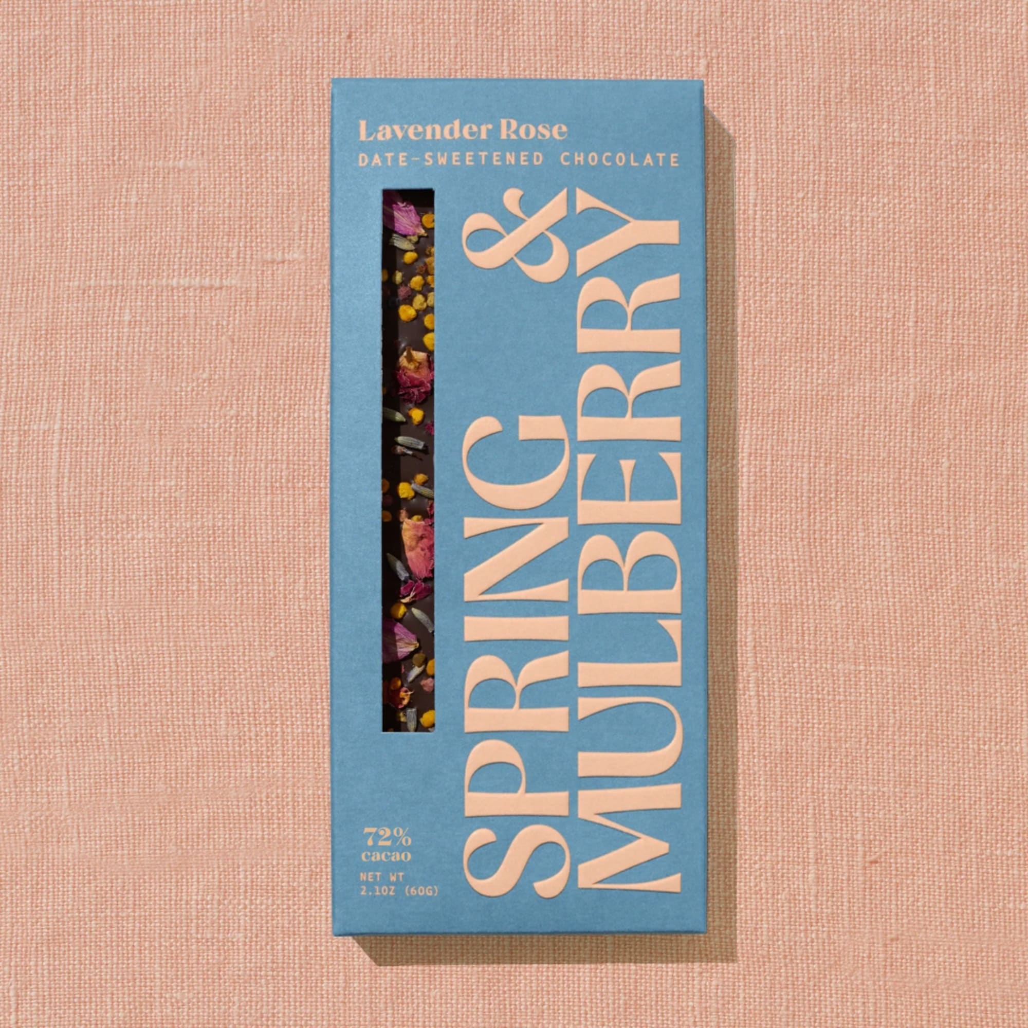 Blue box of lavender rose date-sweetened chocolate on a pink fabric background