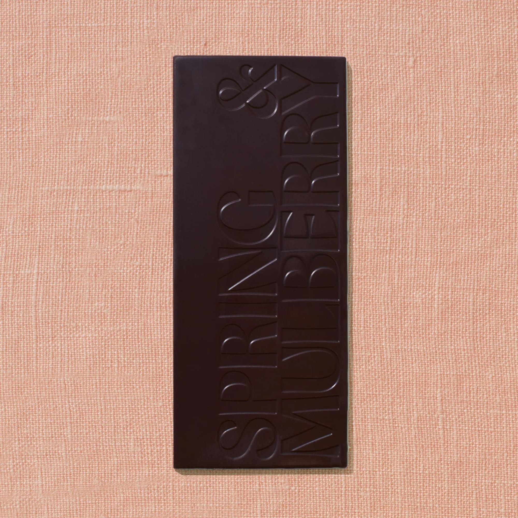 Dark chocolate bar on a peach textured background