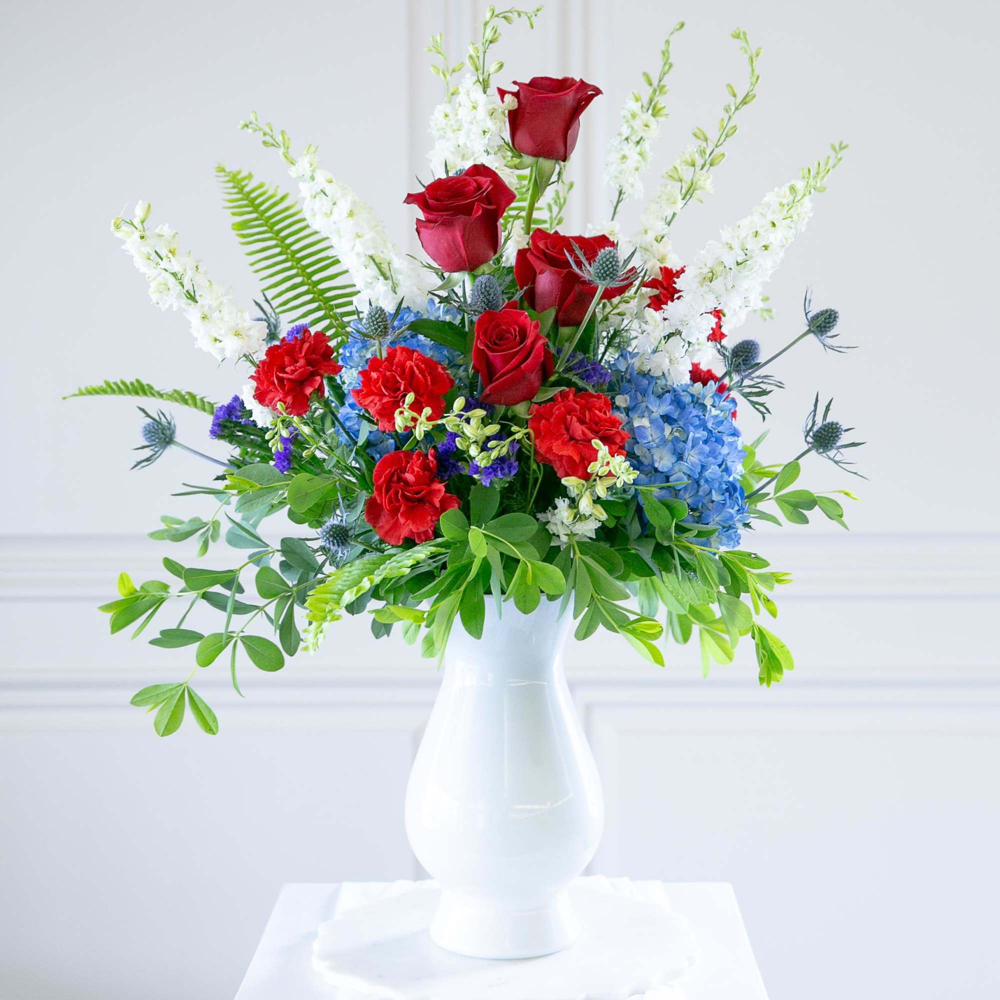 Red roses and blue hydrangeas in a white vase