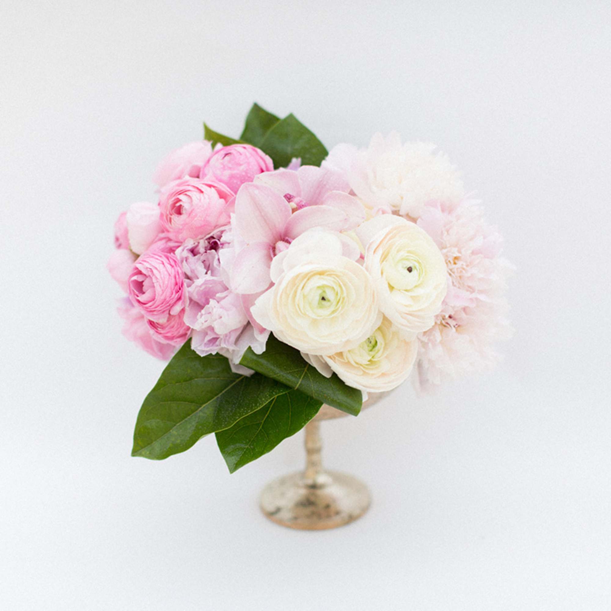 Pink and white floral arrangement in a small pedestal vase