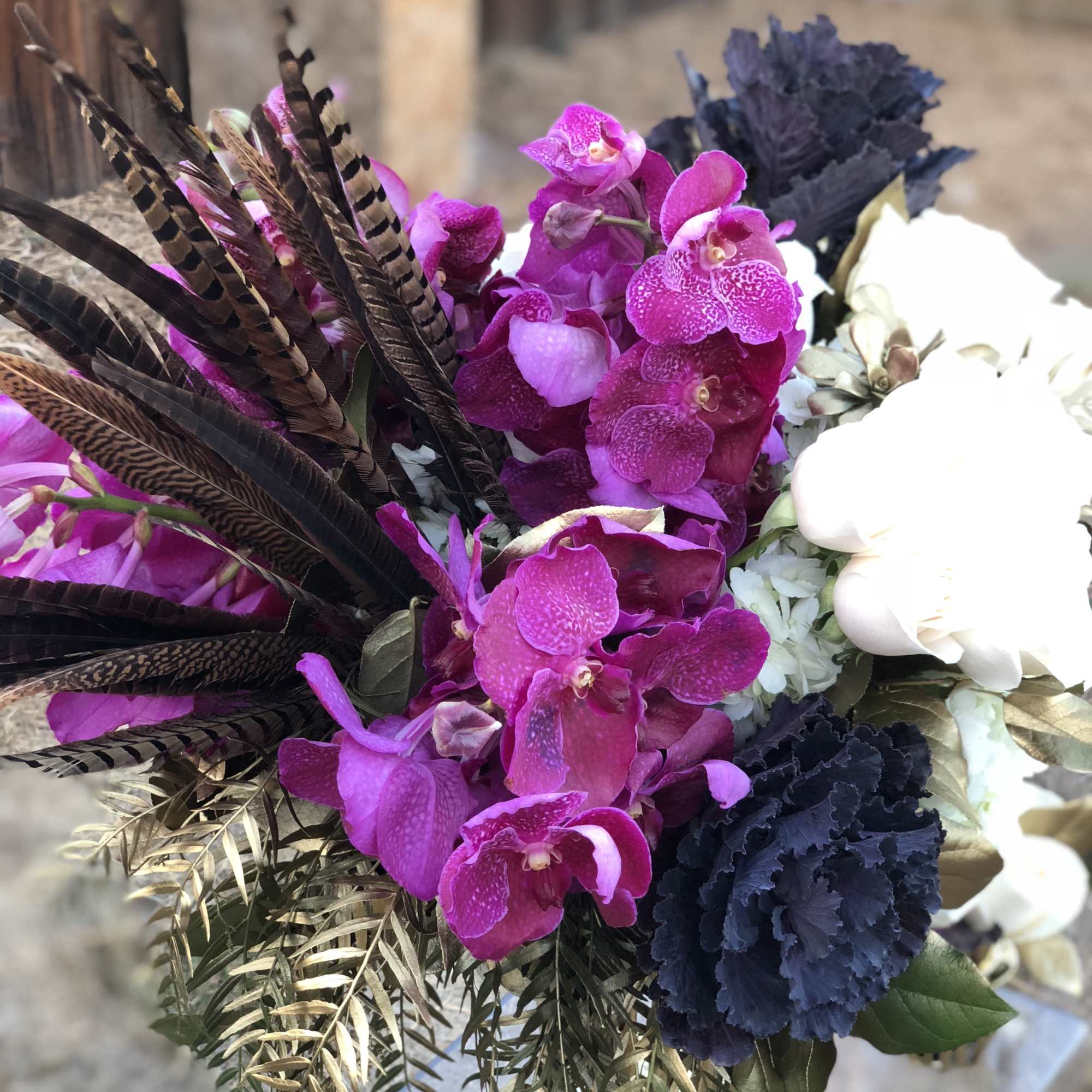 Bouquet of pink orchids with white blooms and dark feathers