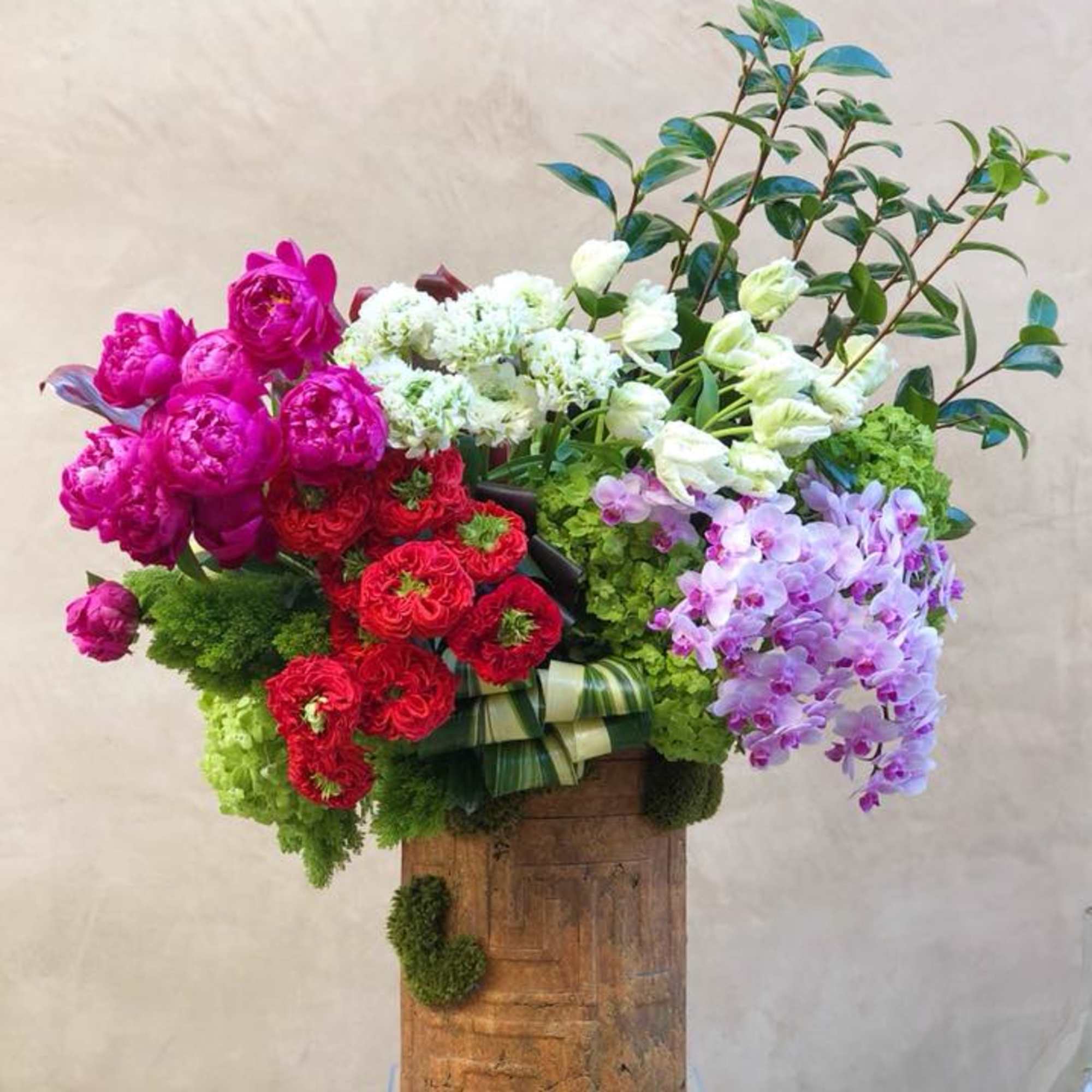 Large mixed bouquet with pink, red, white, and lavender flowers in a wooden container
