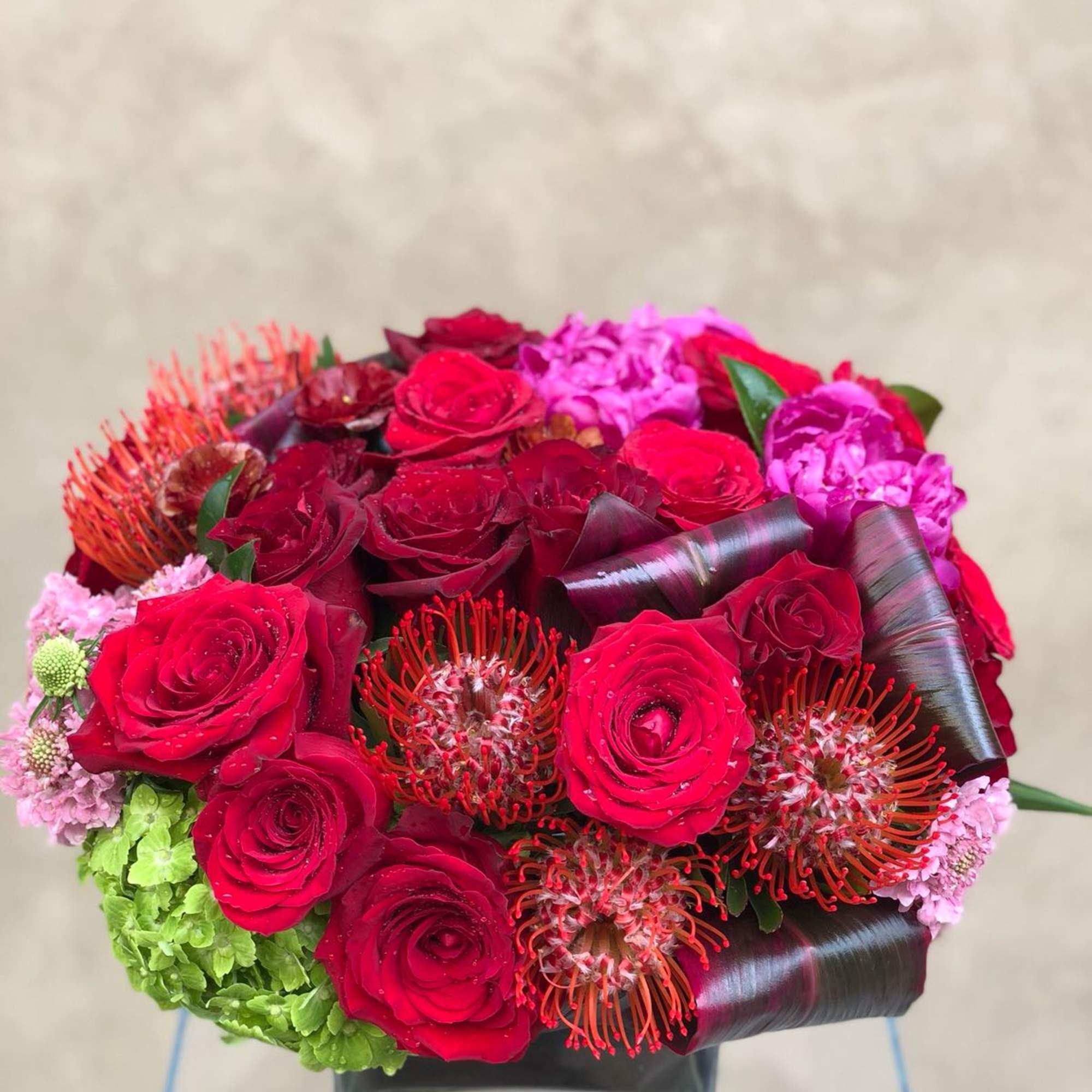 Bouquet of red roses and pink flowers in a square glass vase