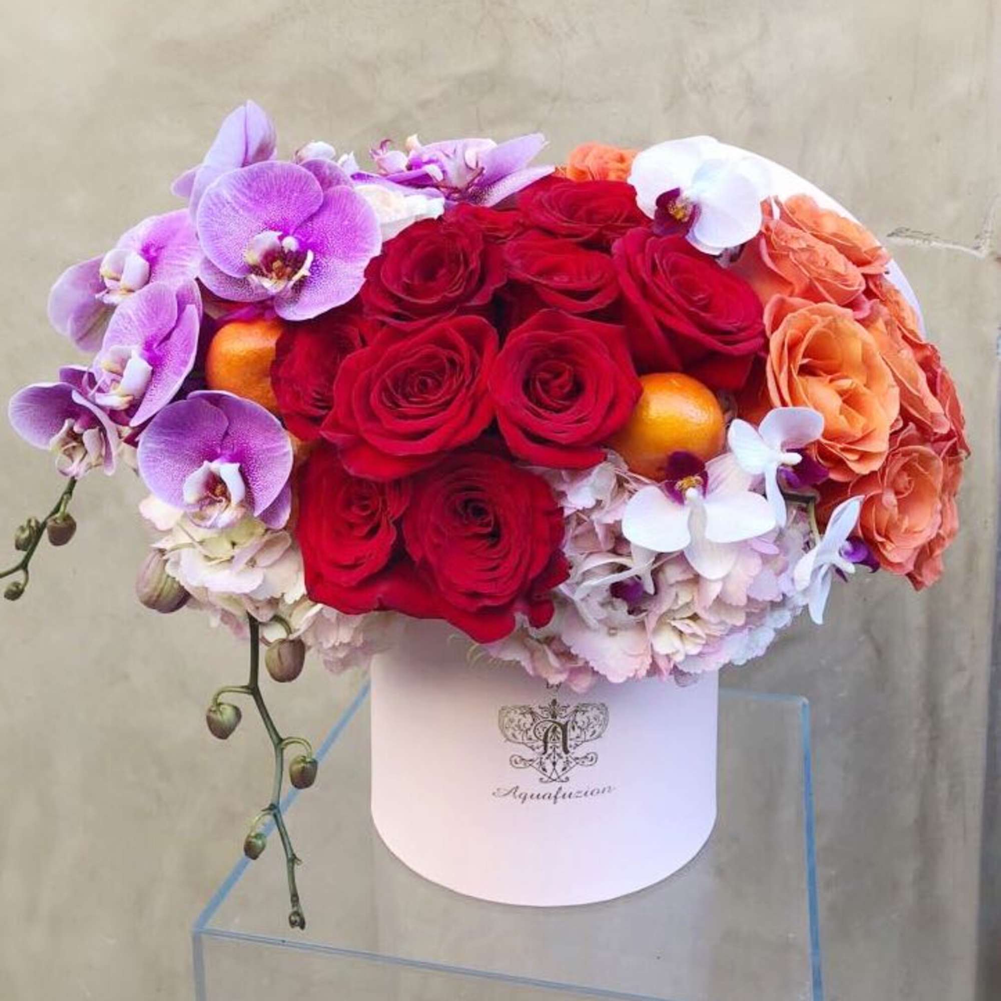 Bouquet of red roses, orchids, and peach flowers in a white hat box