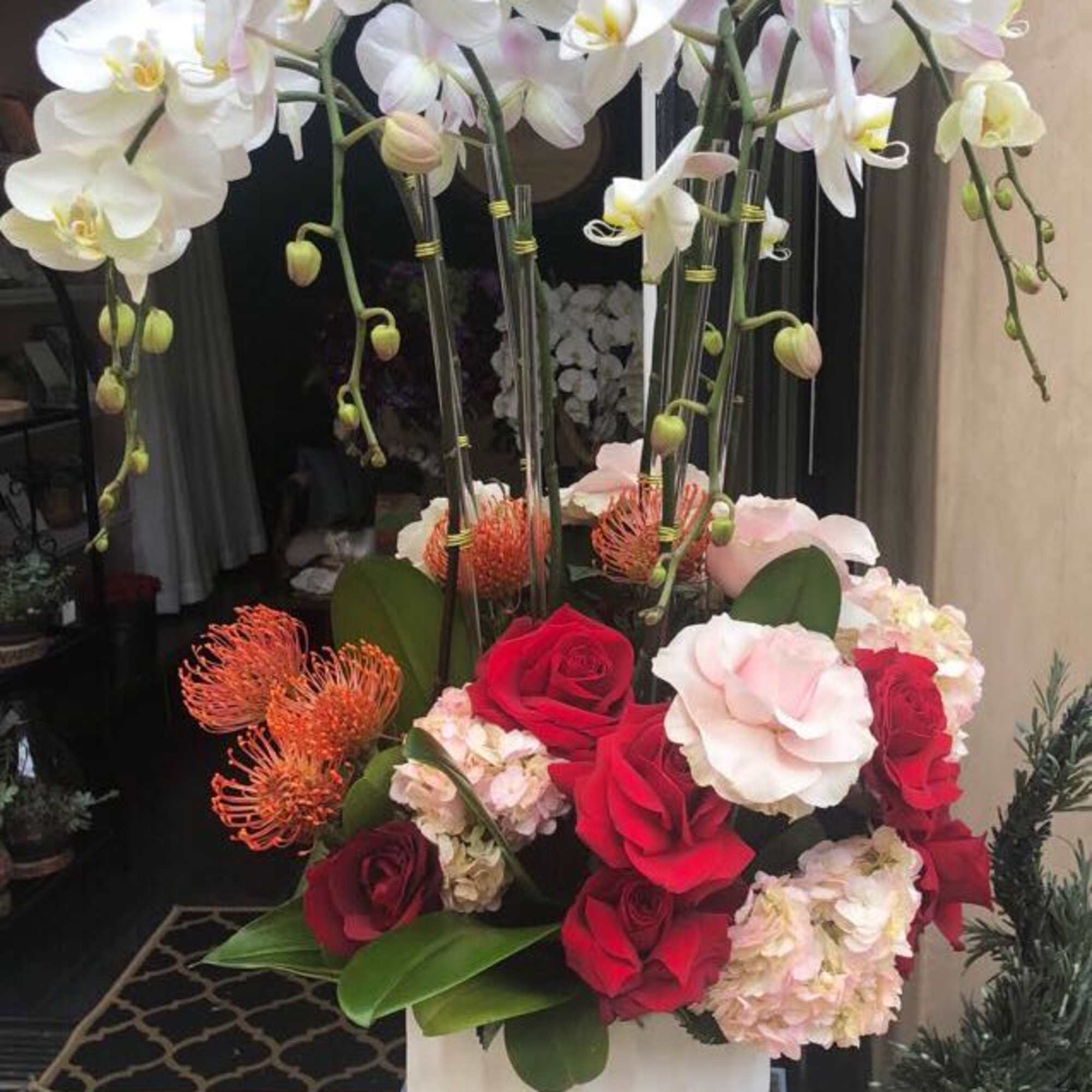 Tall floral arrangement with white orchids and red roses in a white vase, photo 2 of 2