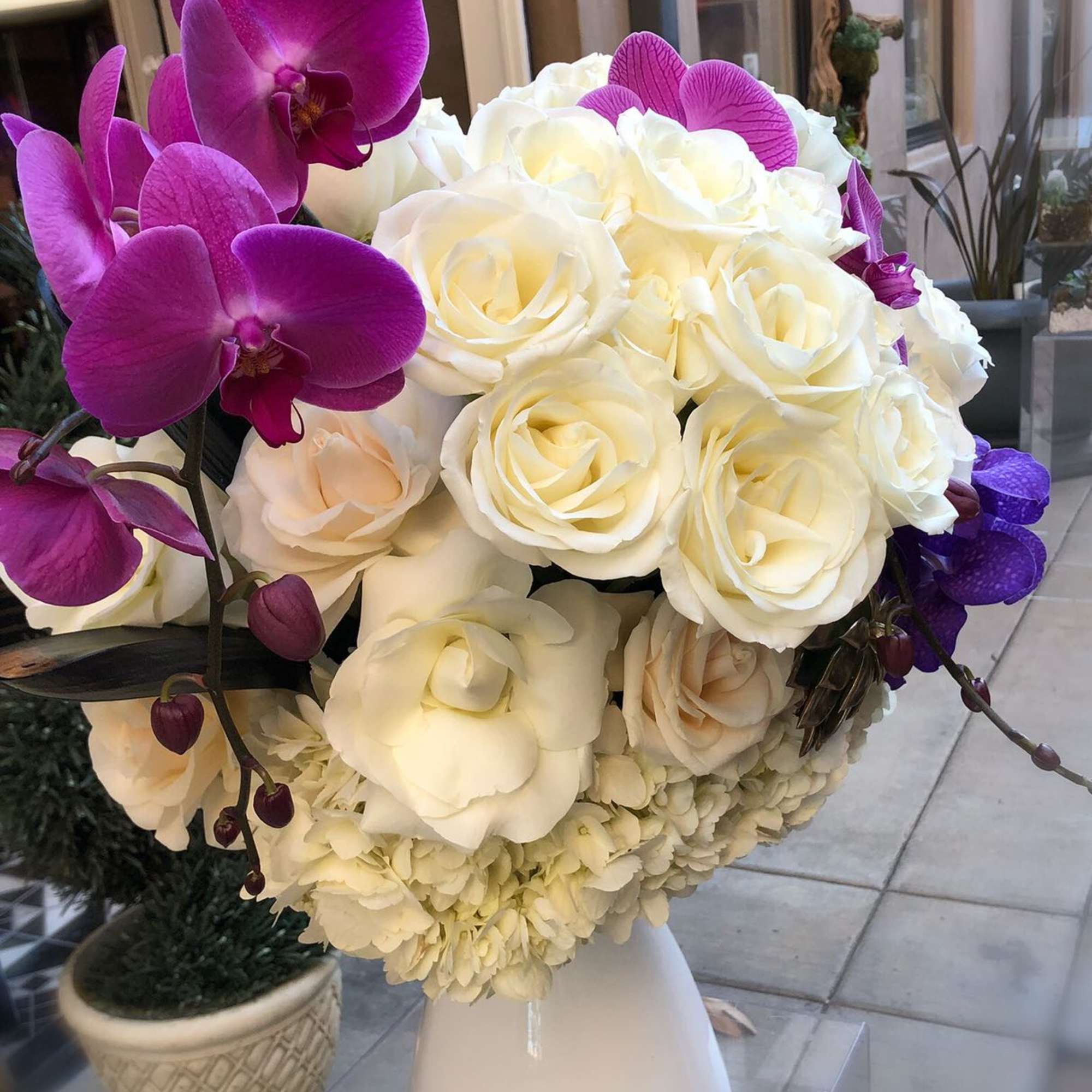 White roses and purple orchids arranged in a white vase, photo 3 of 3