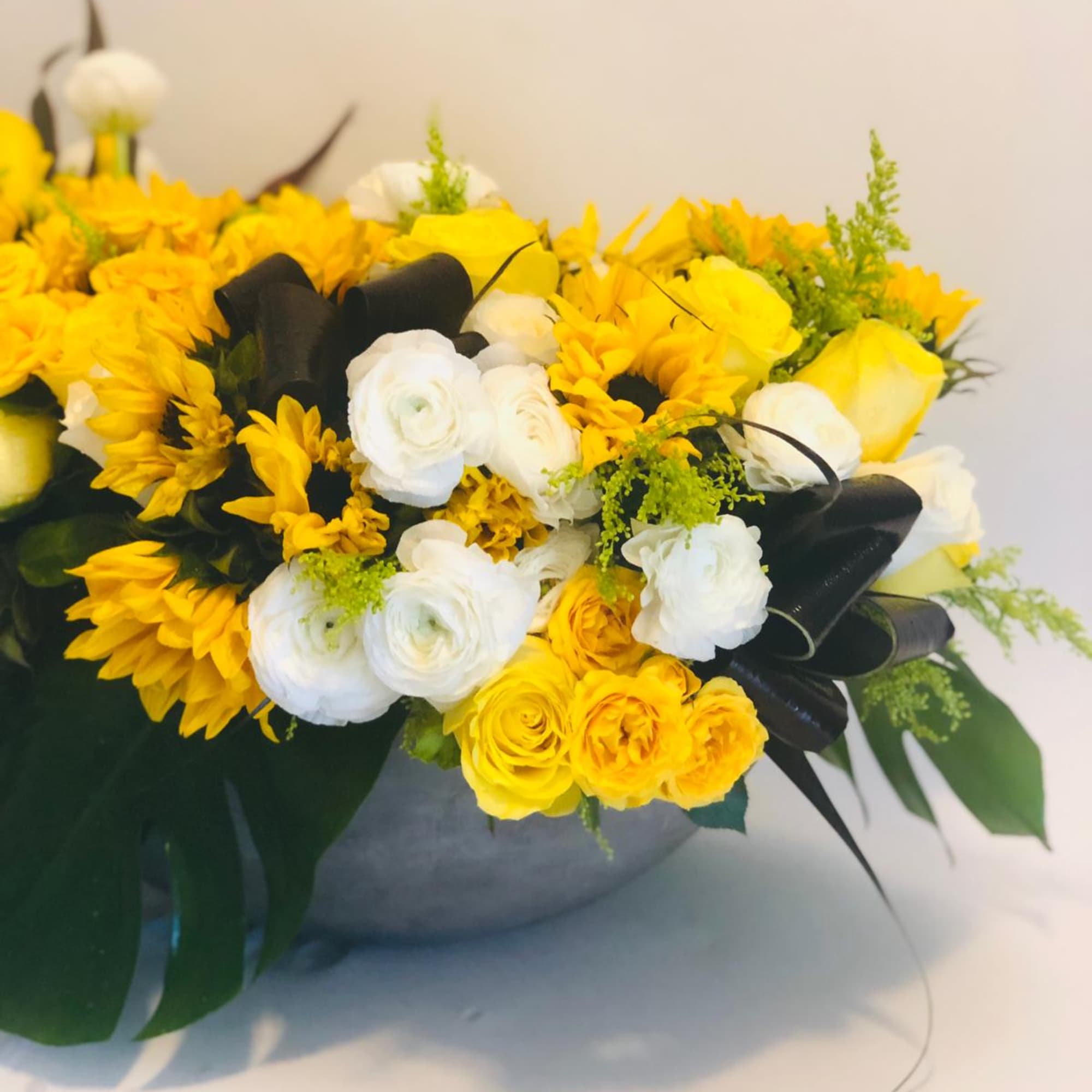 Yellow and white bouquet with black ribbon in a round vase