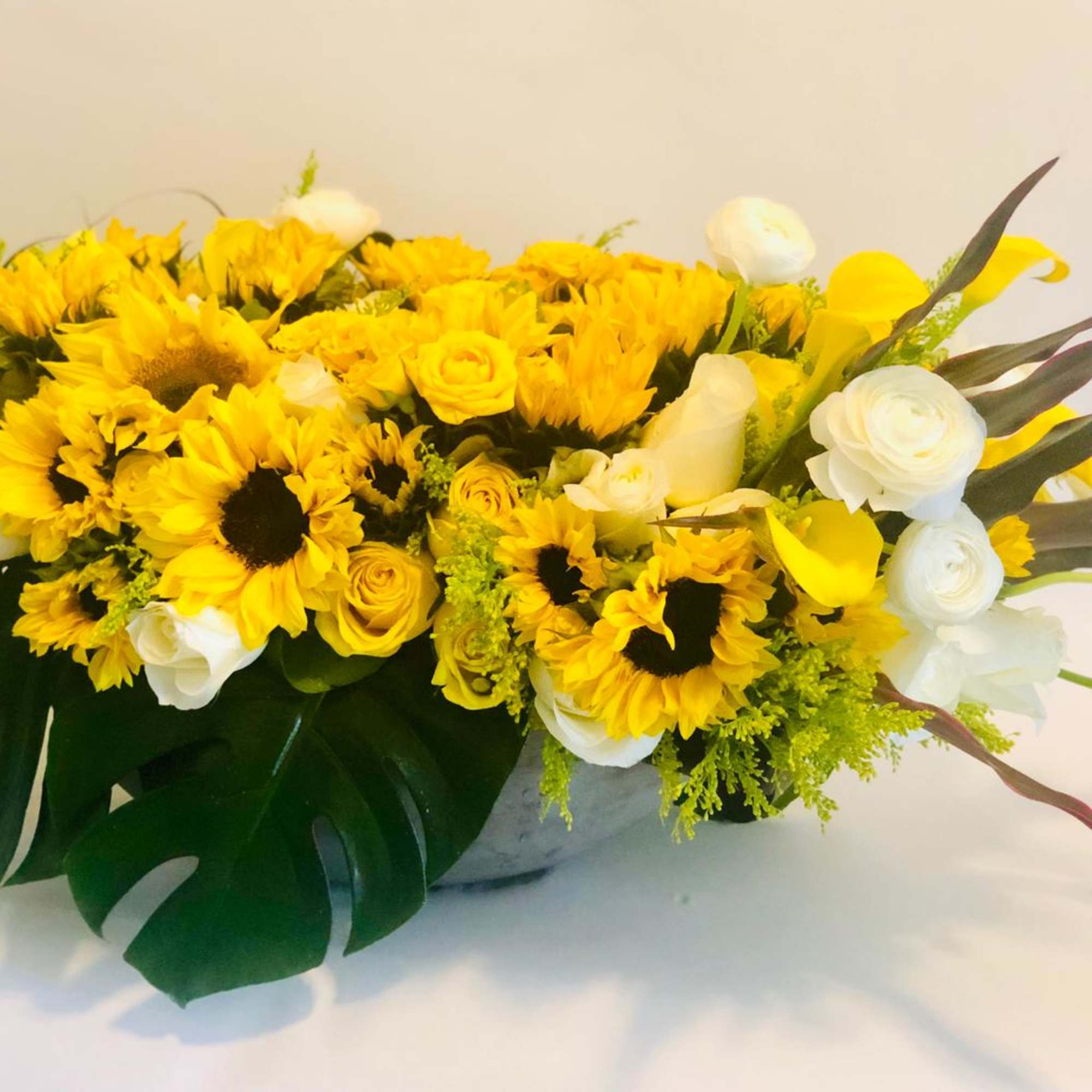 Yellow sunflower and white rose arrangement in a low container