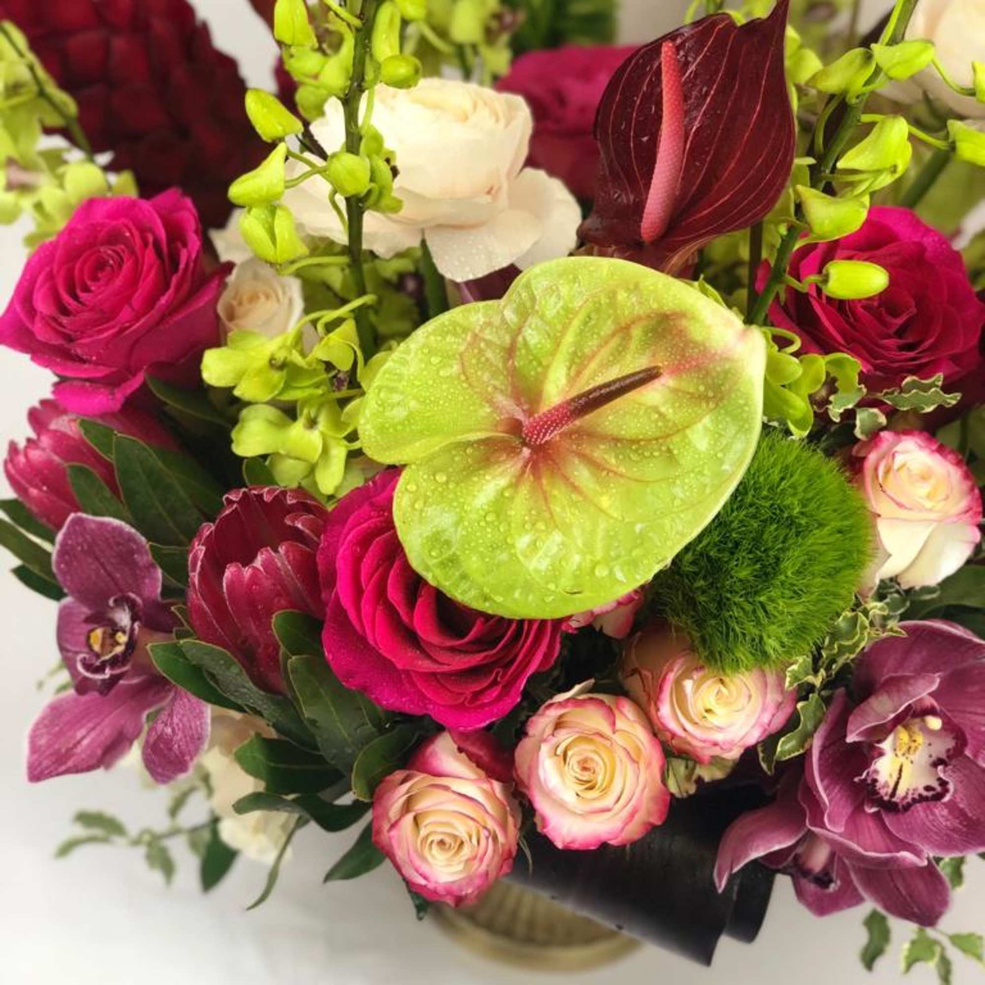 Bouquet with pink roses, orchids, and a green anthurium bloom