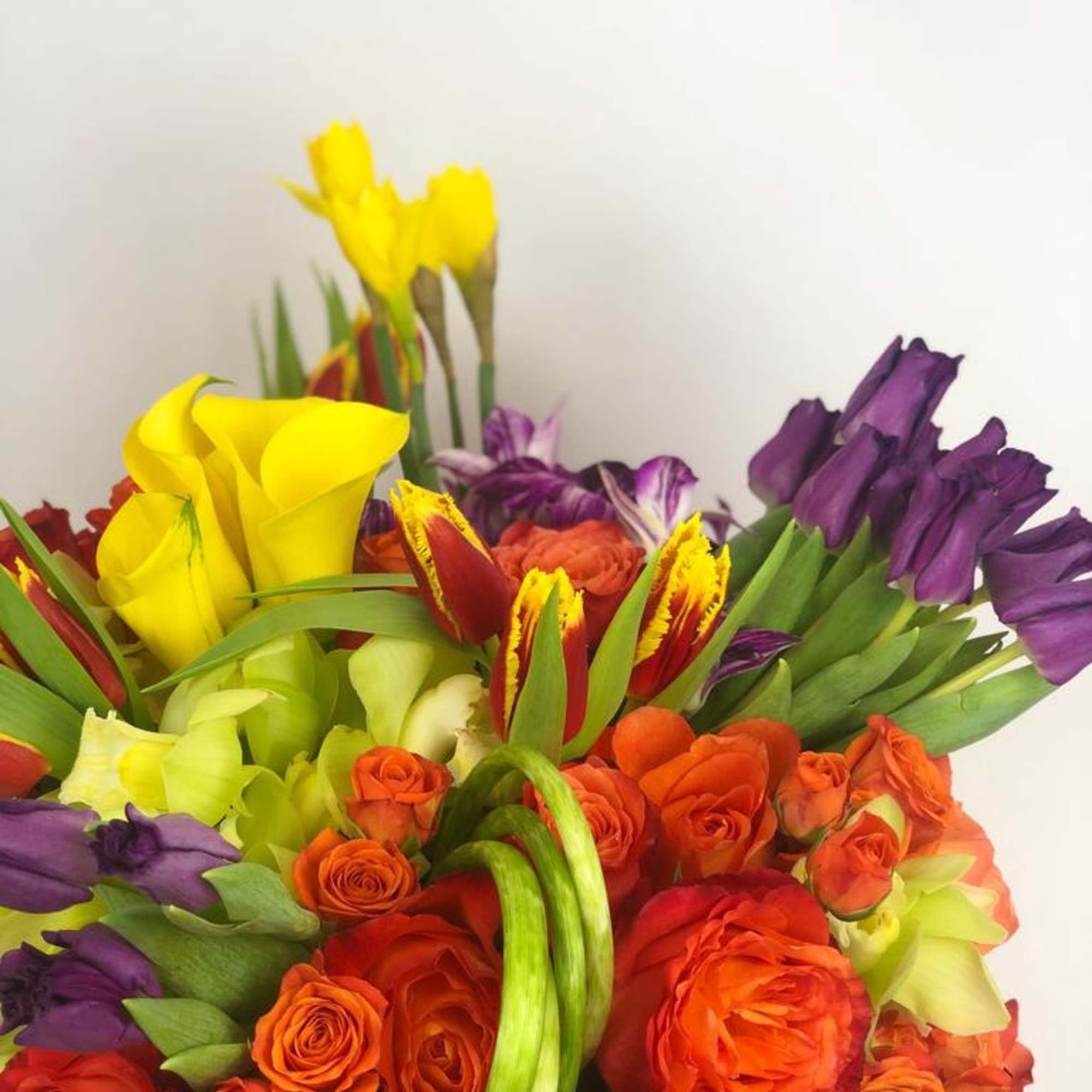 Colorful bouquet with orange roses, yellow calla lilies, and purple tulips