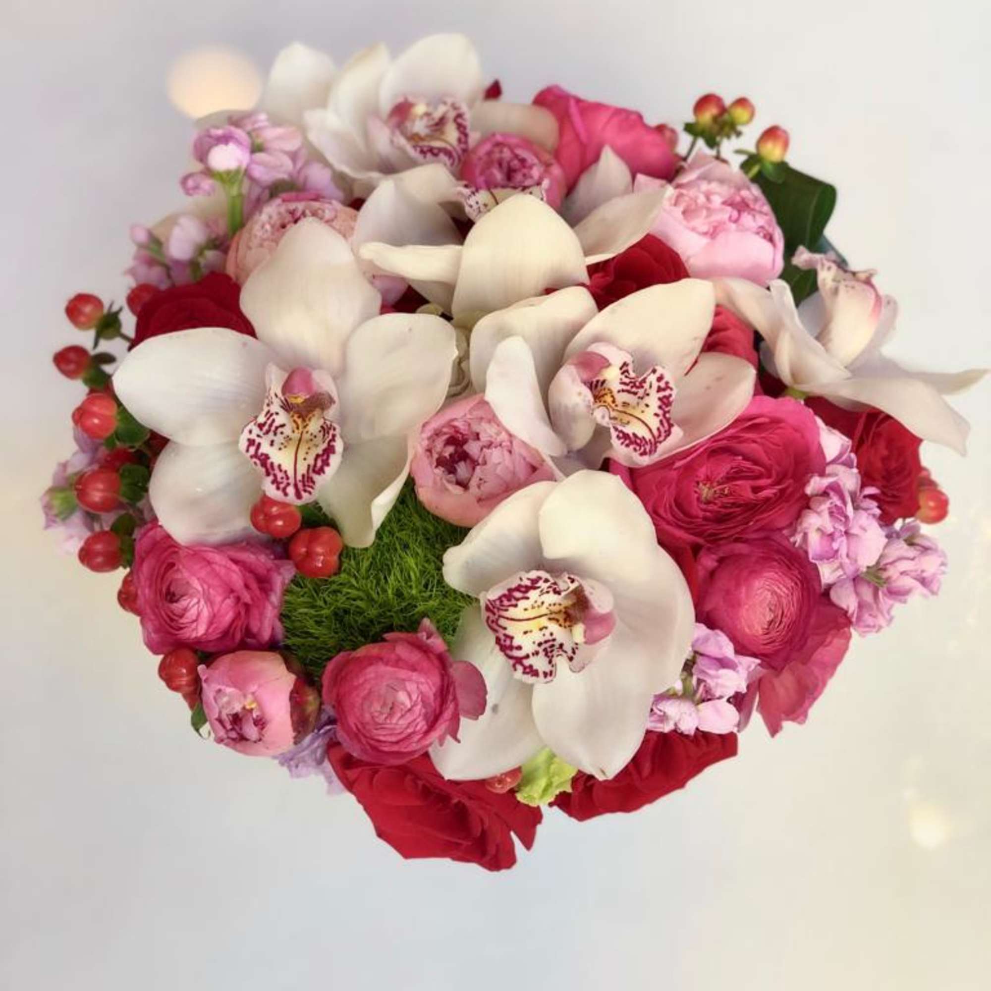 Round bouquet of white orchids, pink roses, and red blooms