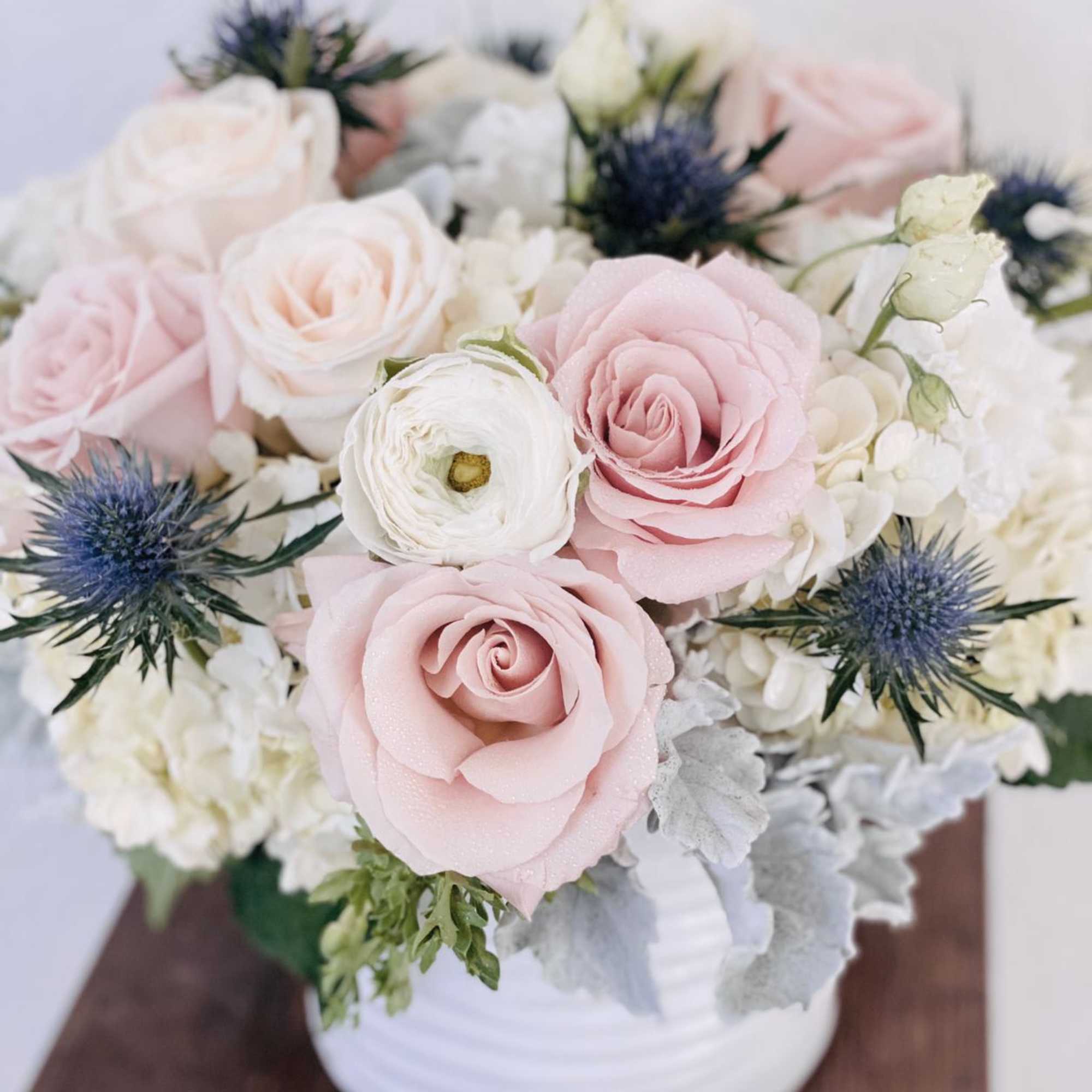 Pink and white roses with blue thistle in a white vase, photo 2 of 3