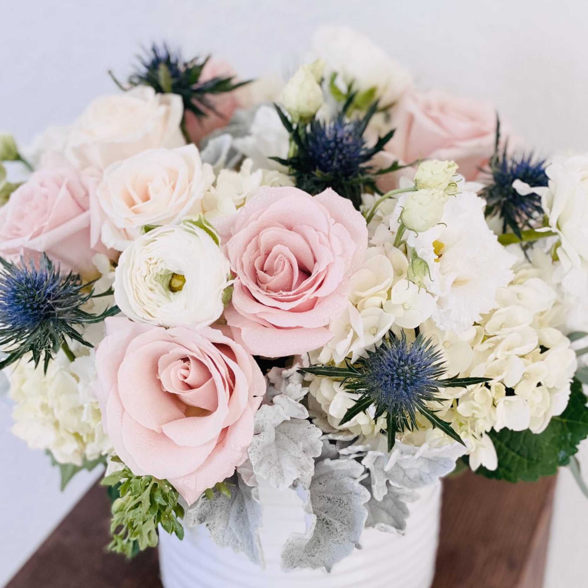Pink and white roses with blue thistle in a white vase, photo 3 of 3