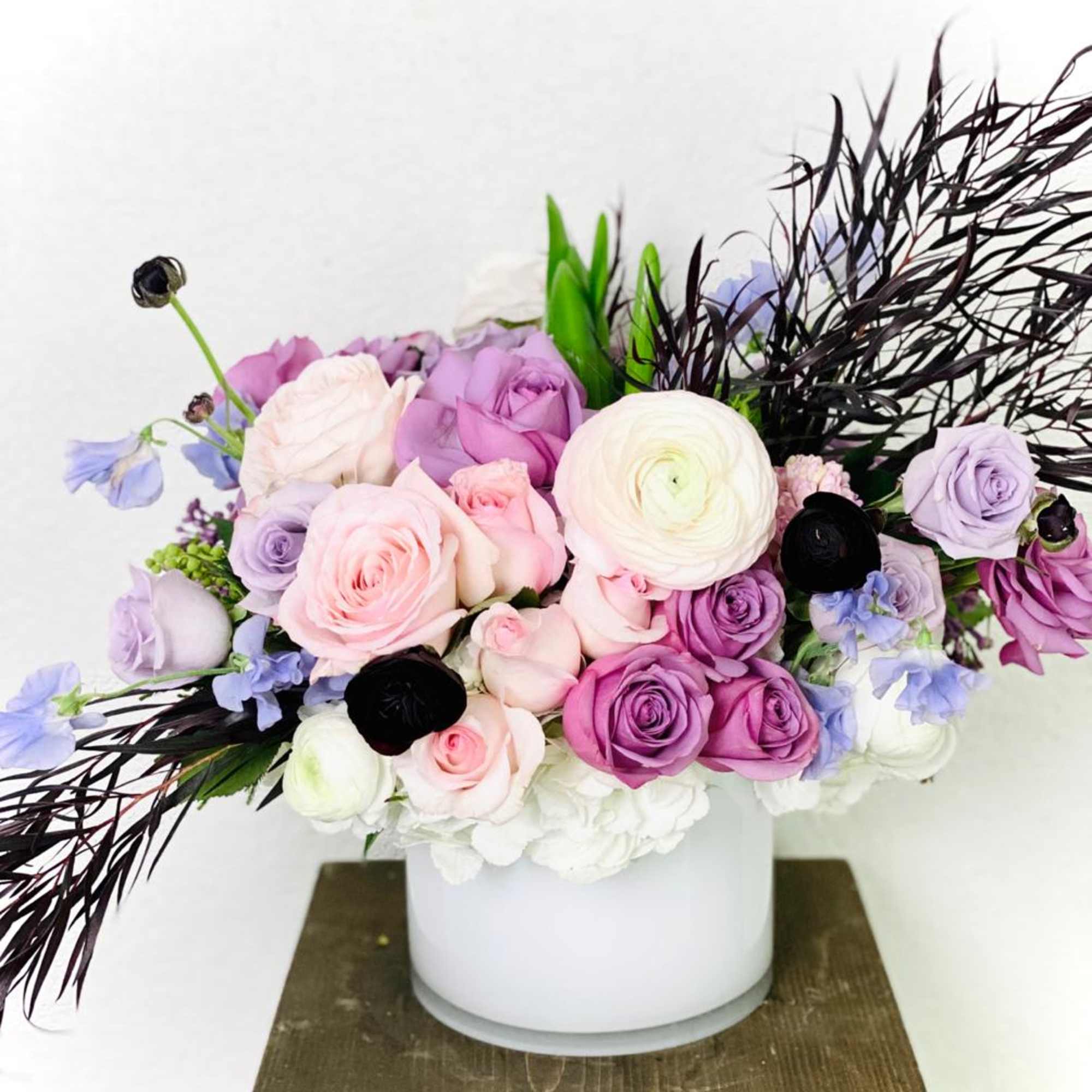 Pastel roses and ranunculus in a white round vase