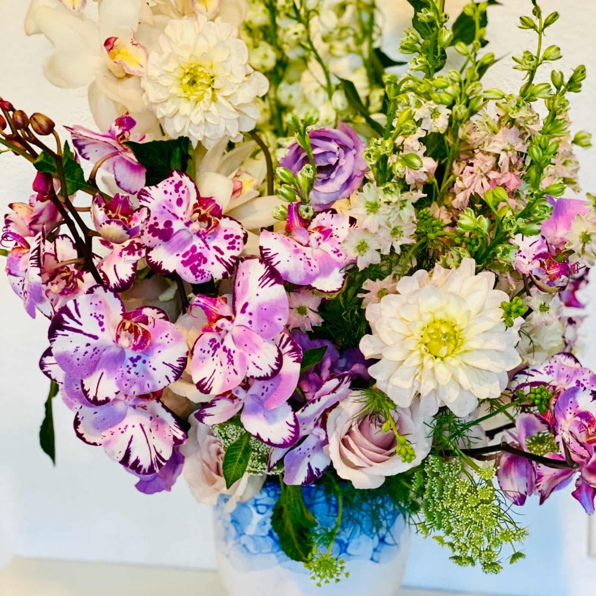 Bouquet of orchids, white dahlias, and pink roses in a white vase