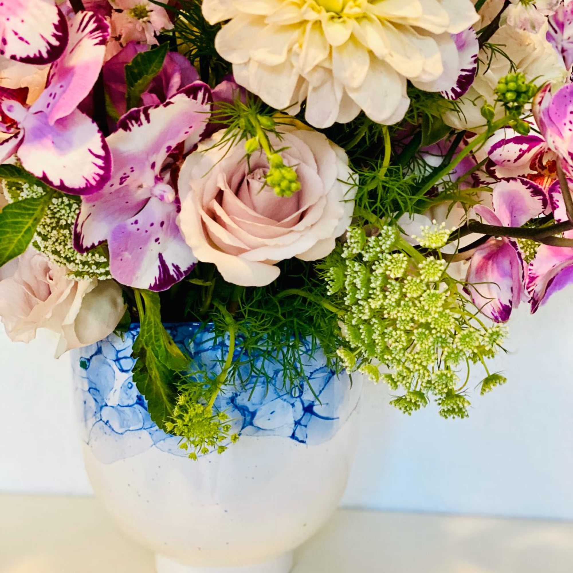 Pink and white flowers arranged in a white vase