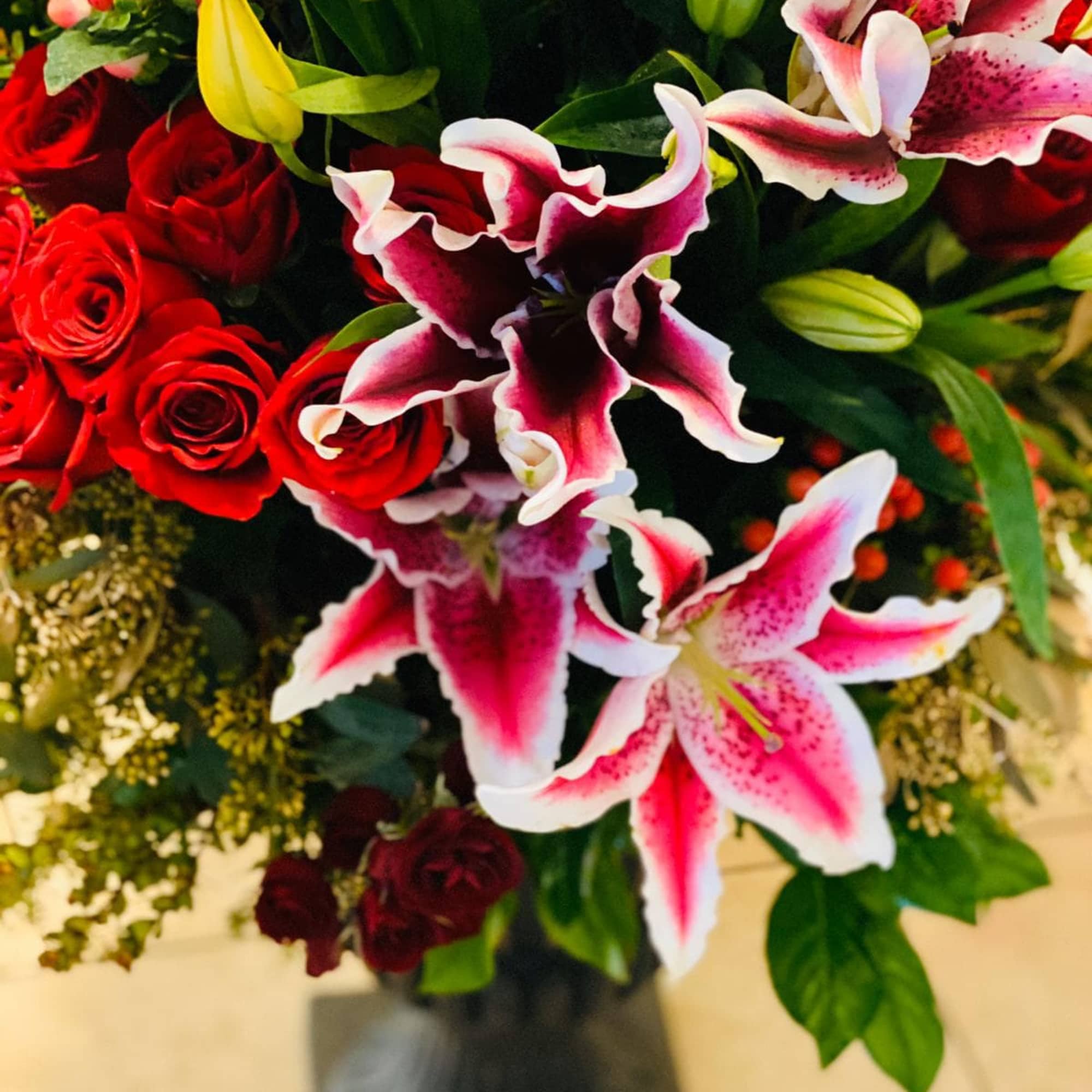 Bouquet of red roses and pink lilies in a black vase