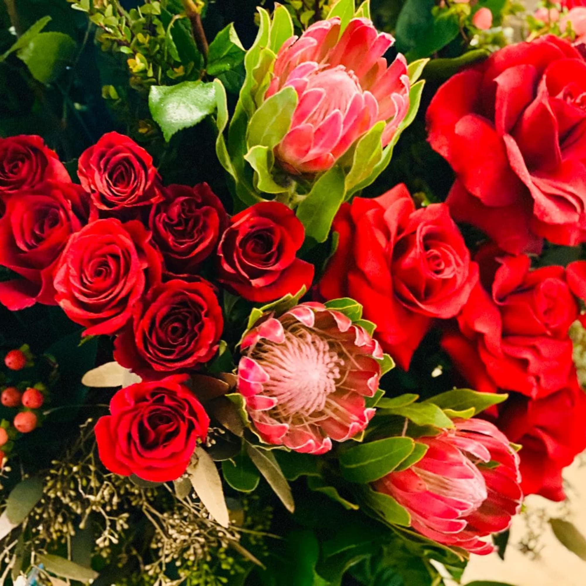 Bouquet of red roses and pink protea flowers