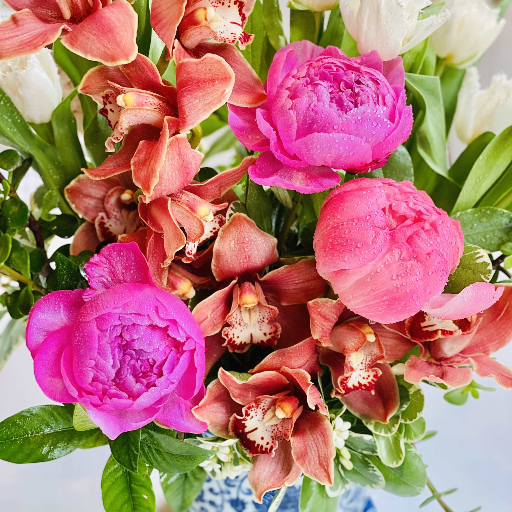 Pink peonies and red orchids in a blue-and-white vase