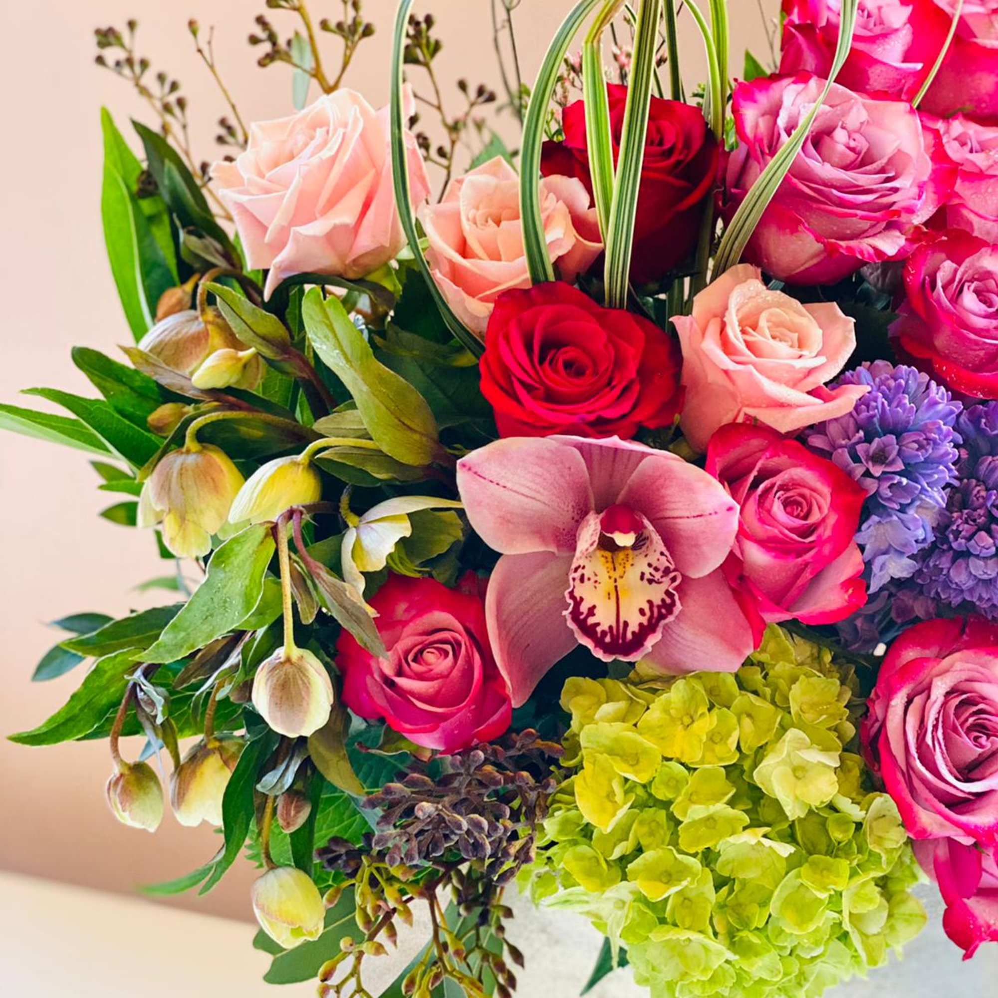Mixed bouquet of pink and red roses with orchids and hydrangea in a vase