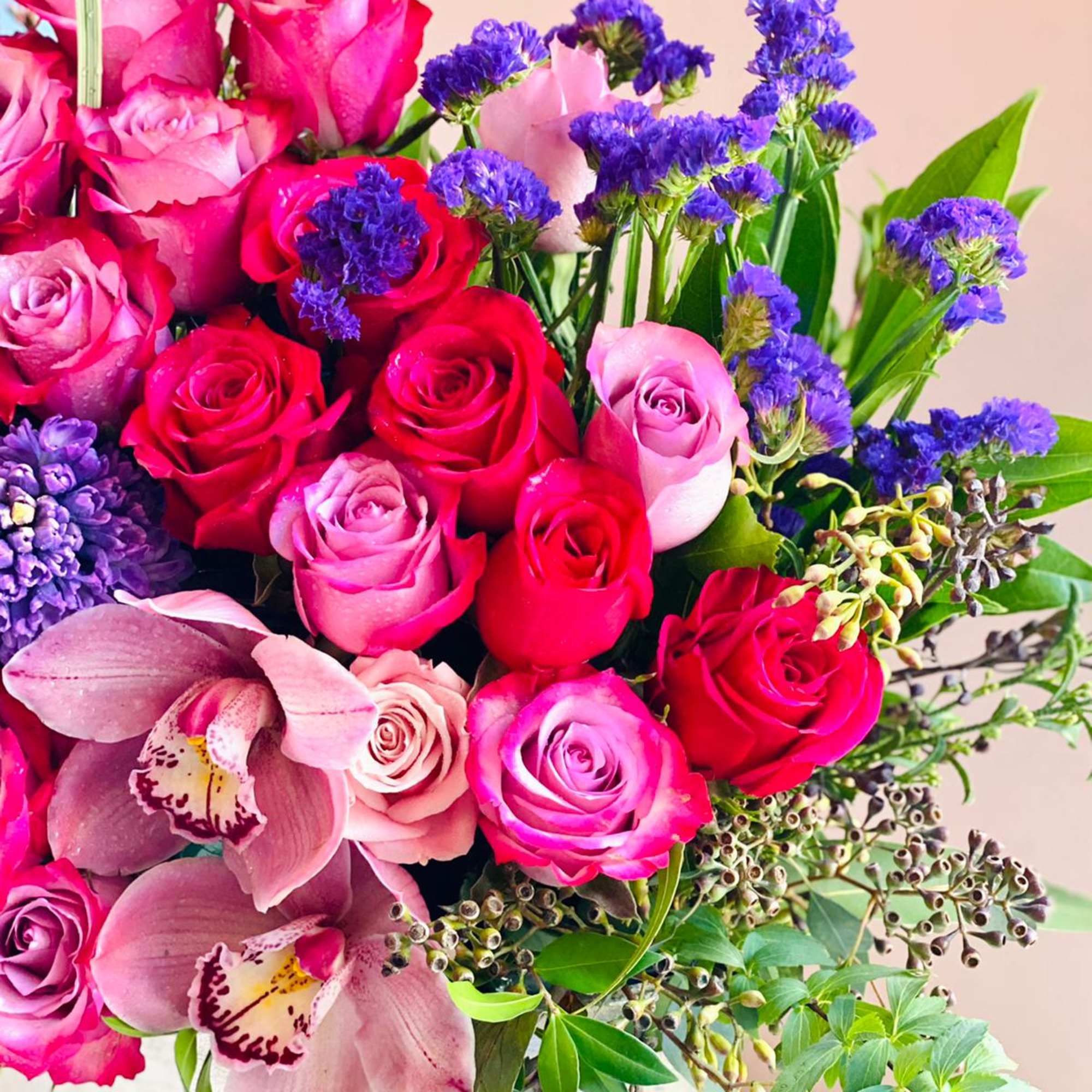 Bouquet of pink and red roses with orchids and purple filler flowers