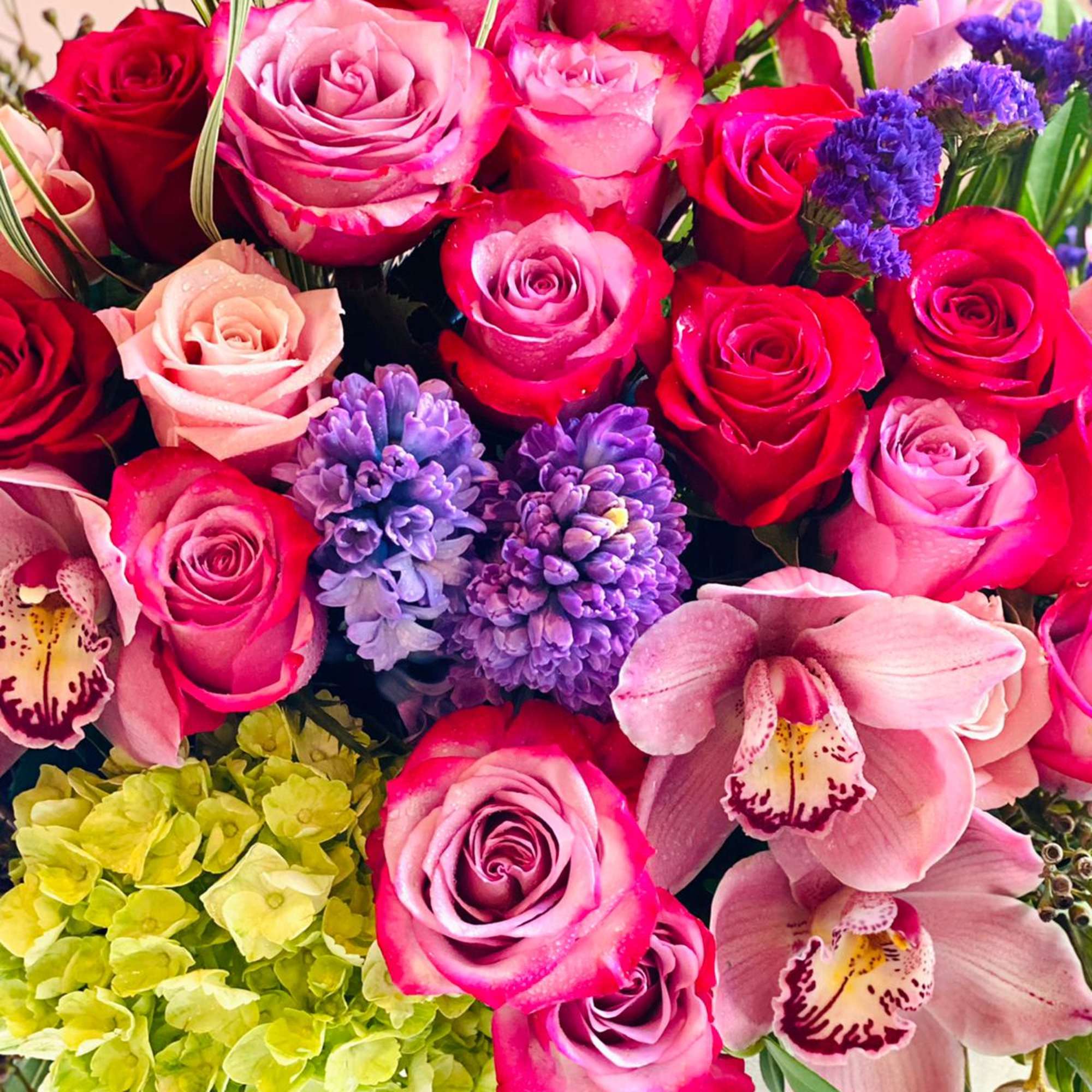 Bouquet of pink and red roses with purple blooms and orchids