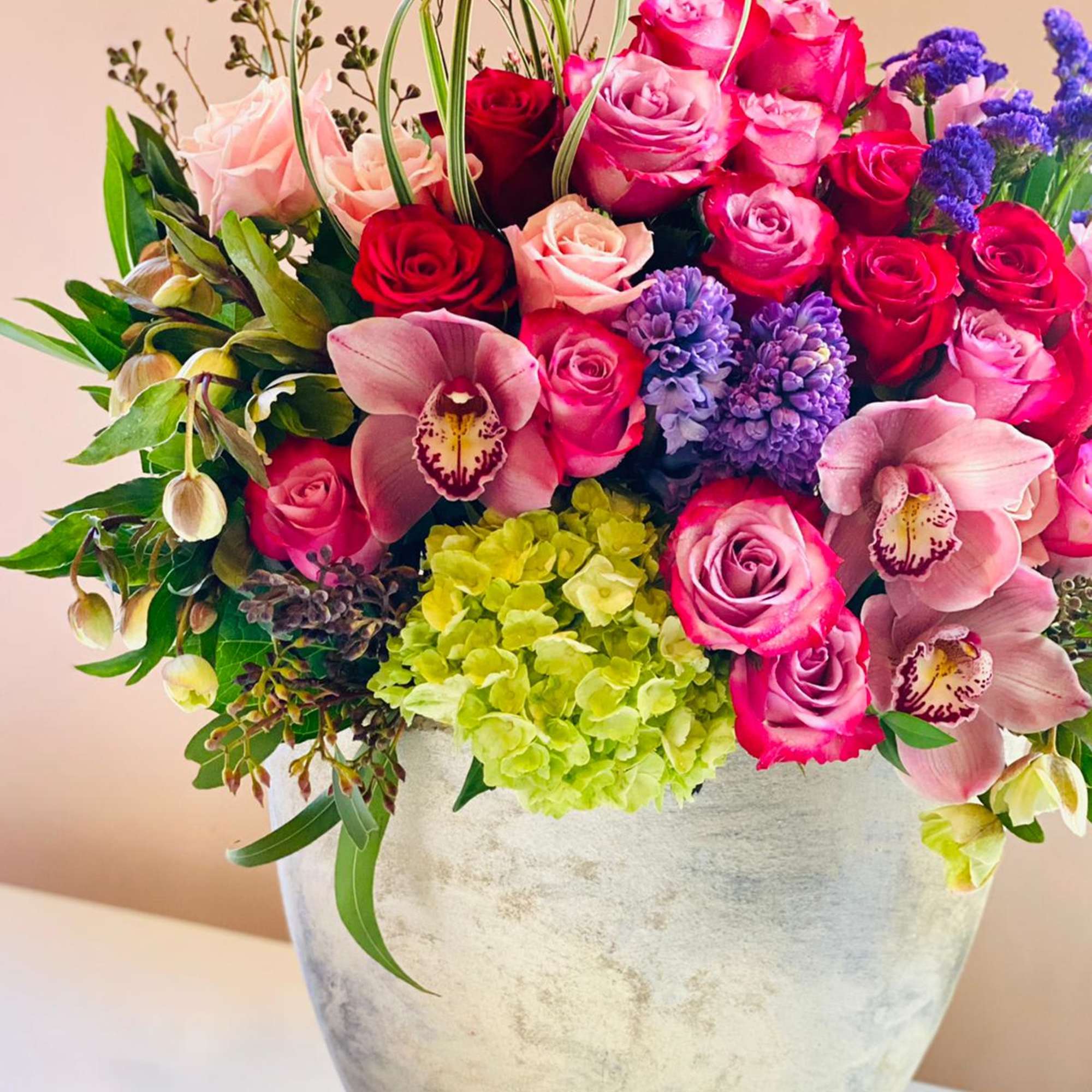Pink and red roses with orchids and hydrangea in a vase
