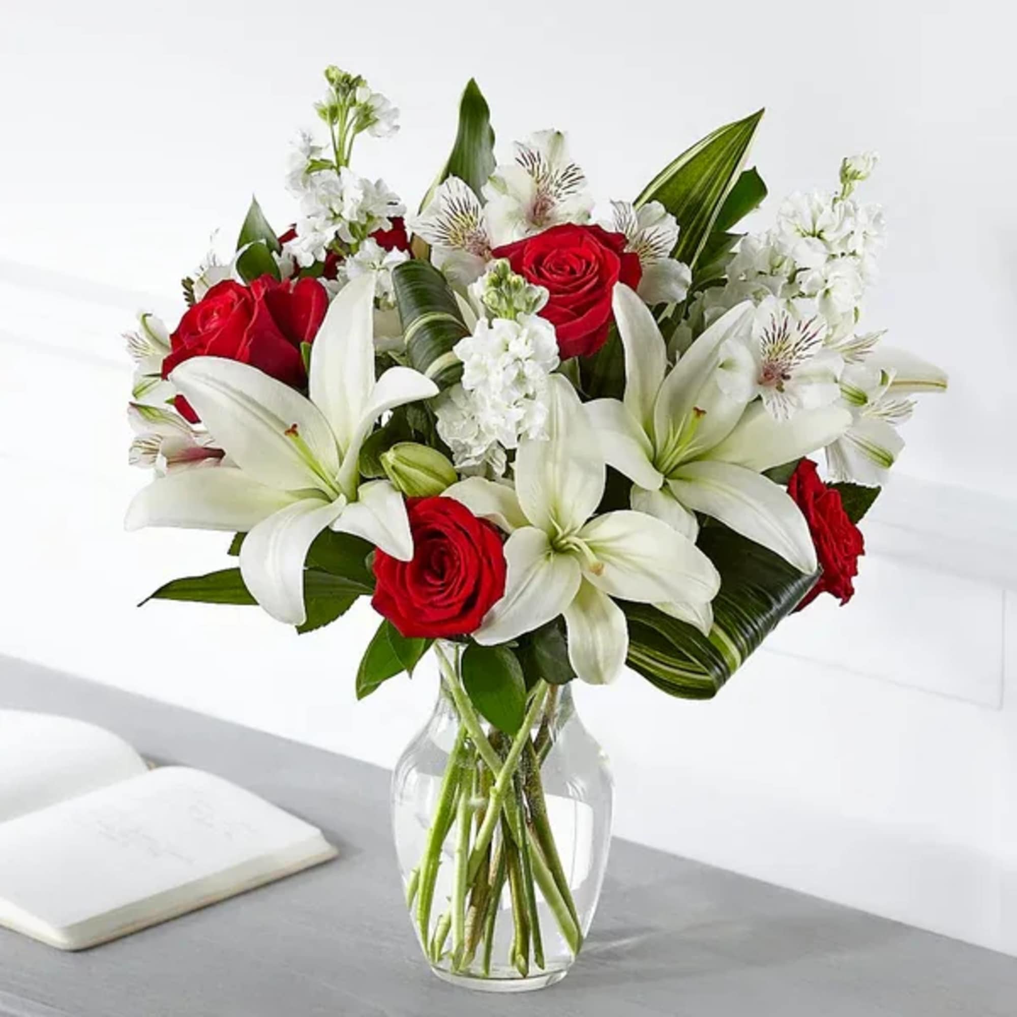 Bouquet of red roses and white lilies in a clear glass vase