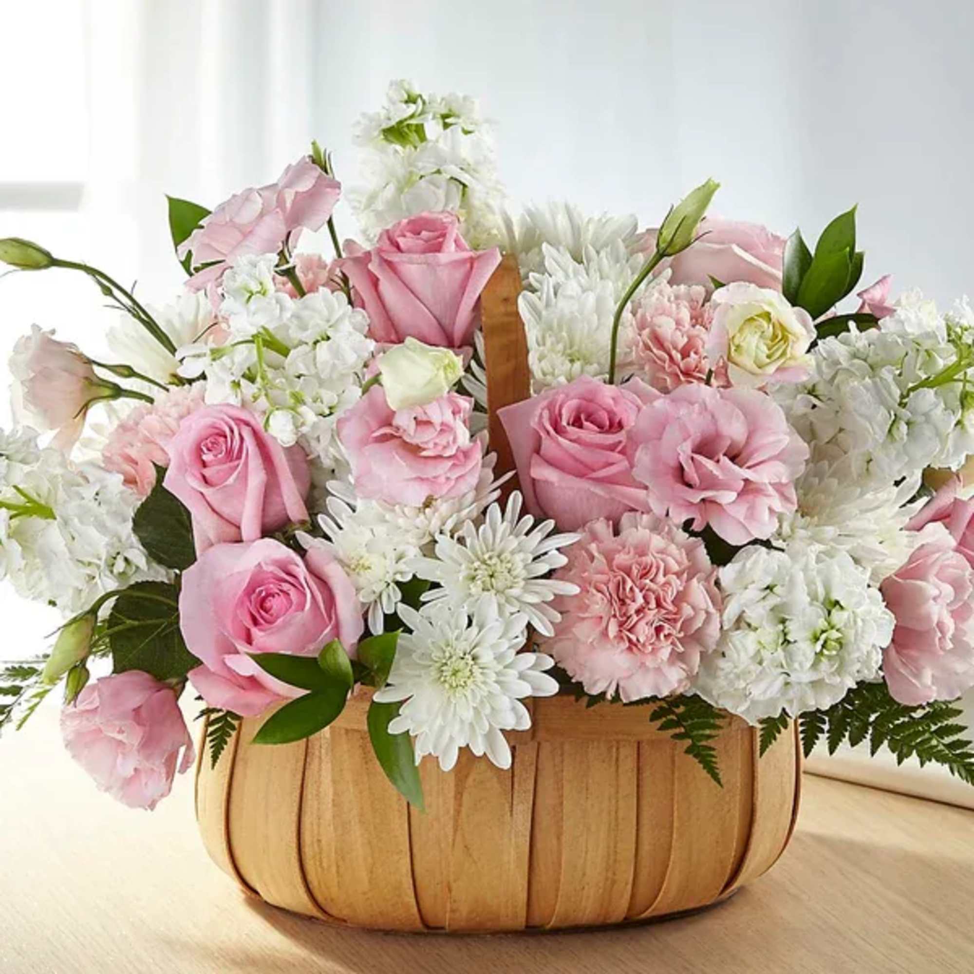 Pink roses and white flowers arranged in a wooden basket