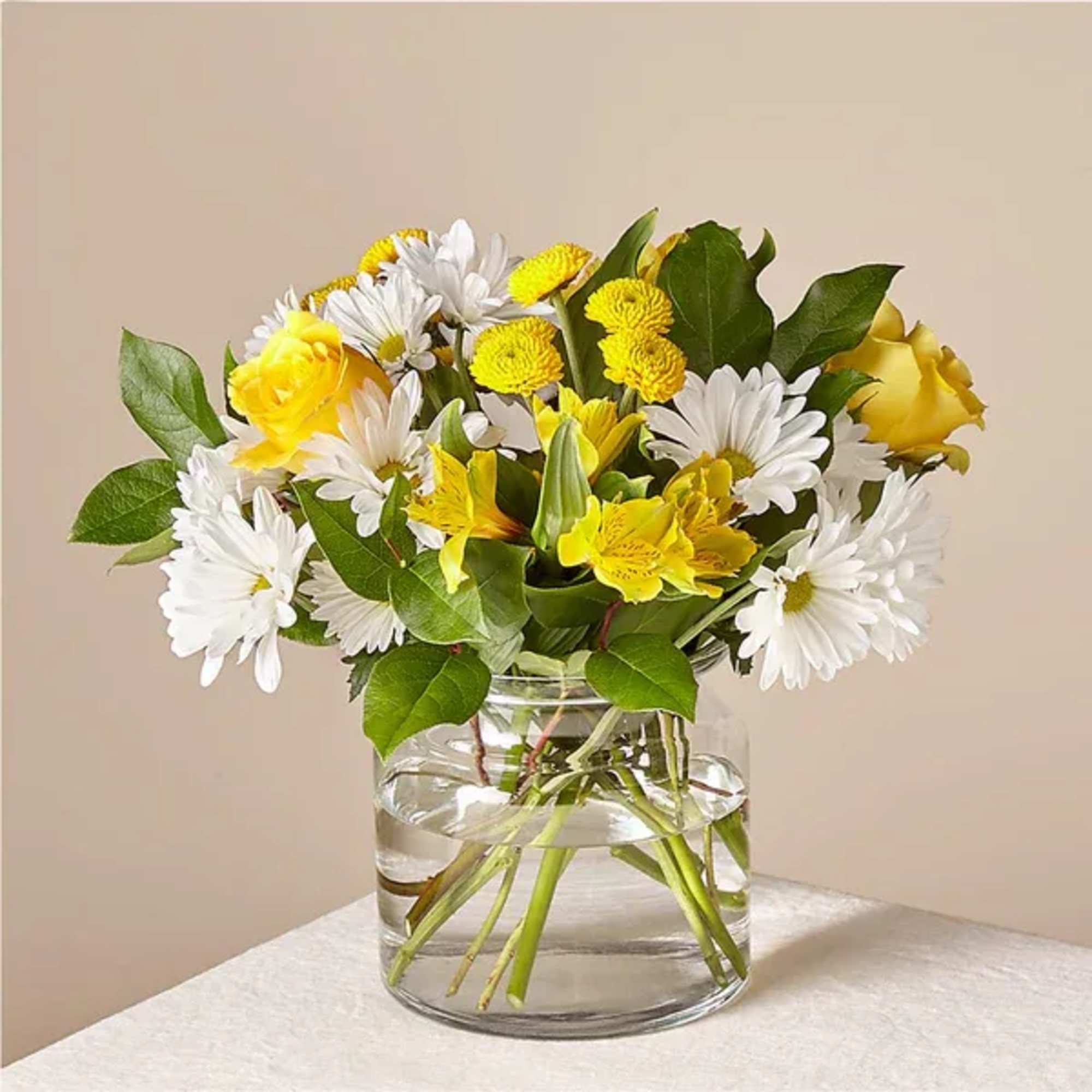 Yellow and white flowers arranged in a clear glass vase