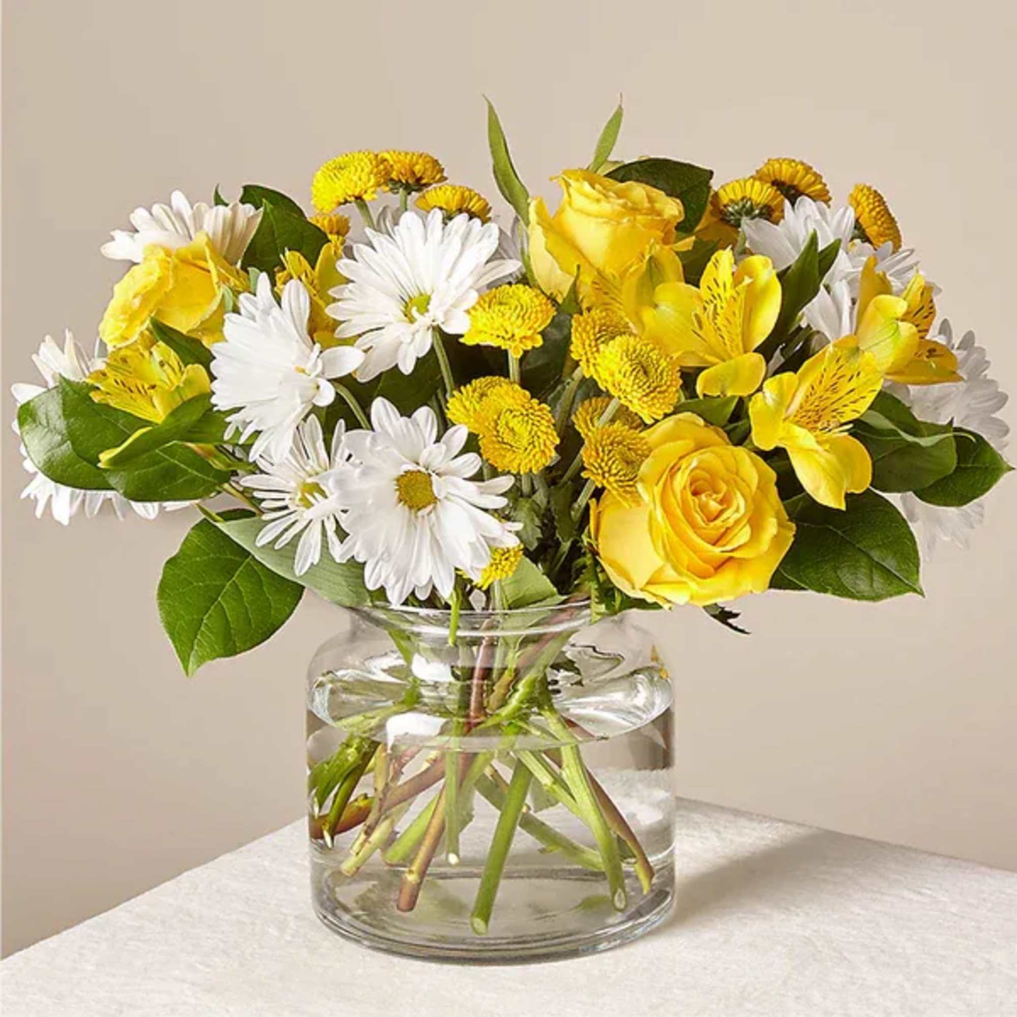 Yellow roses and white daisies in a clear glass vase