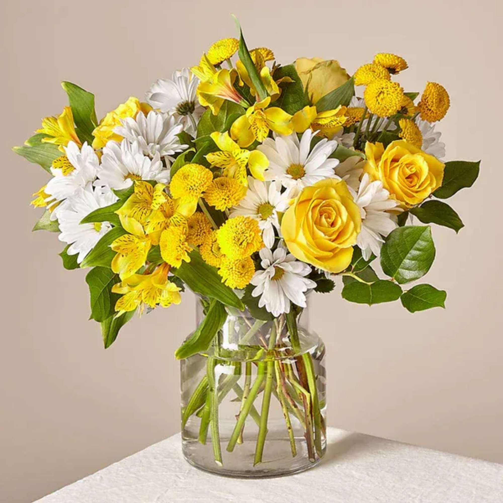 Yellow roses and white daisies in a clear glass vase