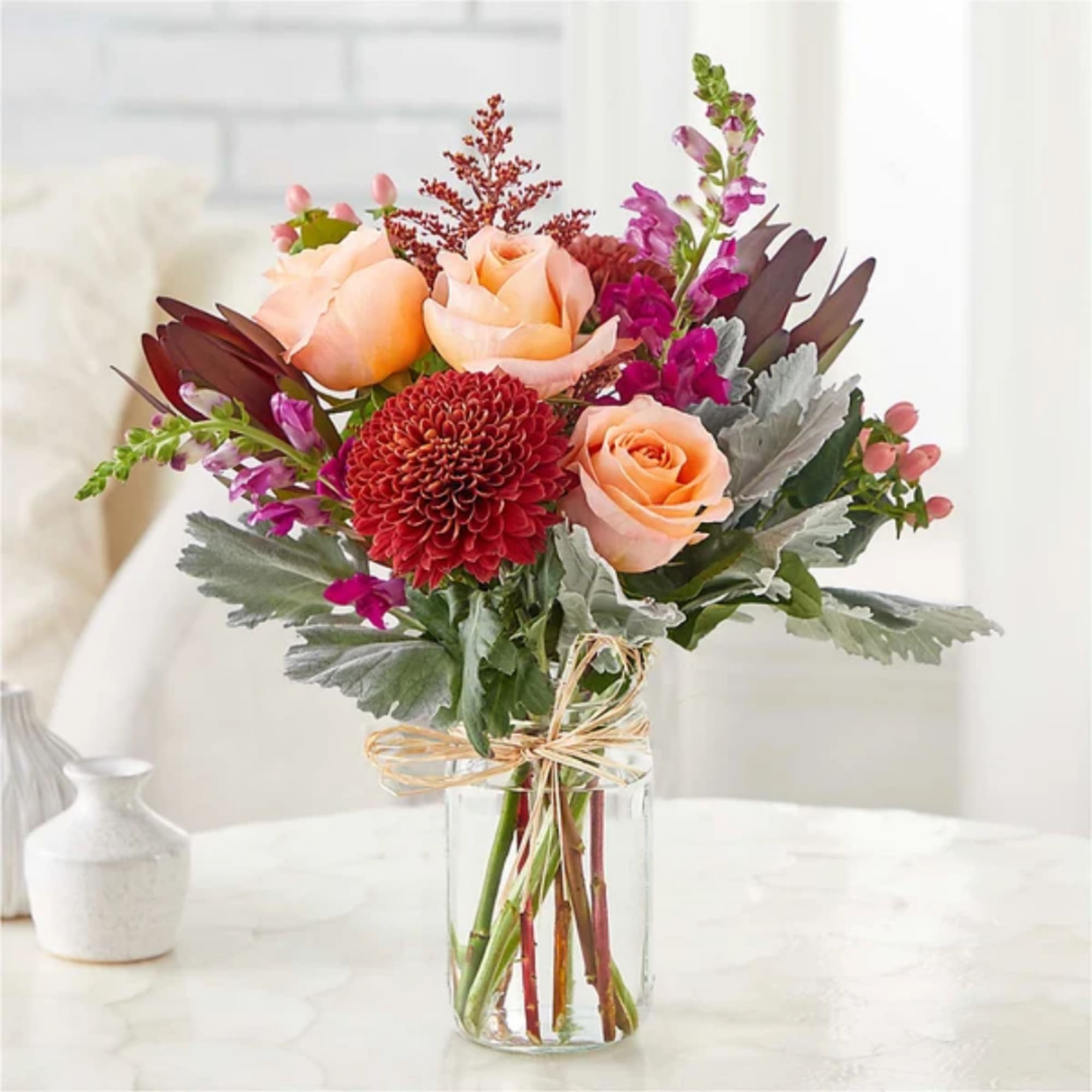 Peach roses and red chrysanthemum bouquet in a clear glass vase