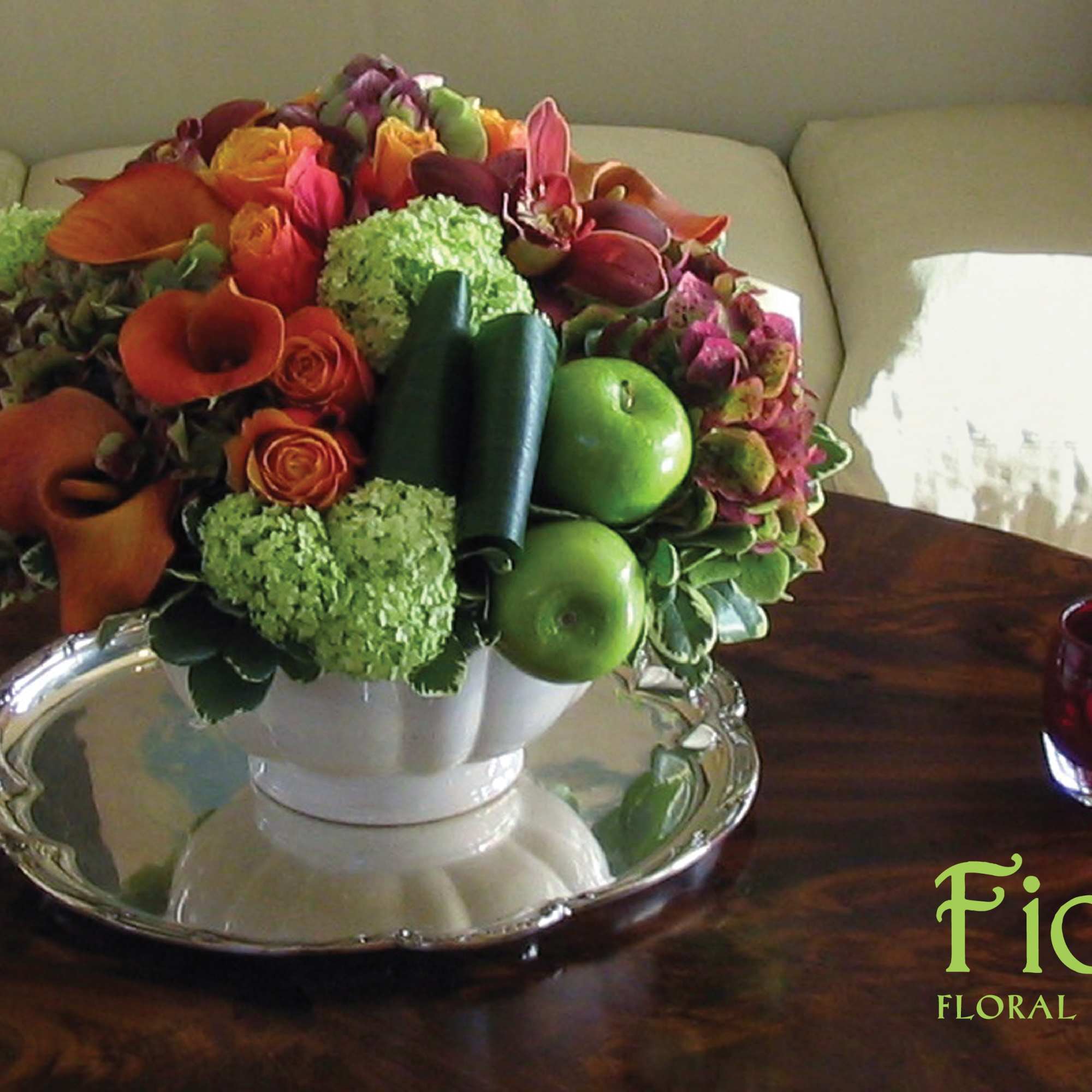 Colorful floral centerpiece in a white bowl with green apples
