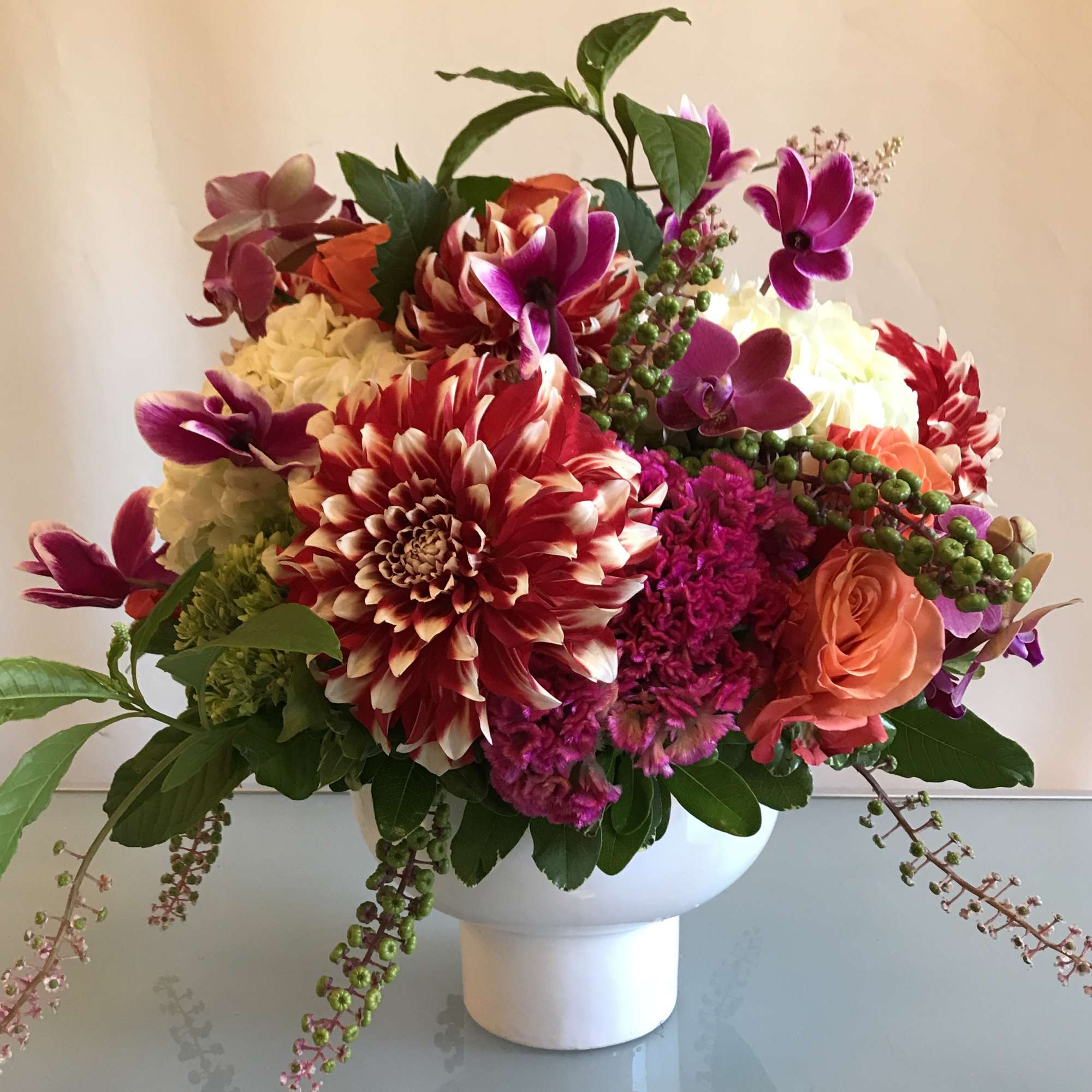 Mixed bouquet of dahlias, roses, and orchids in a white vase