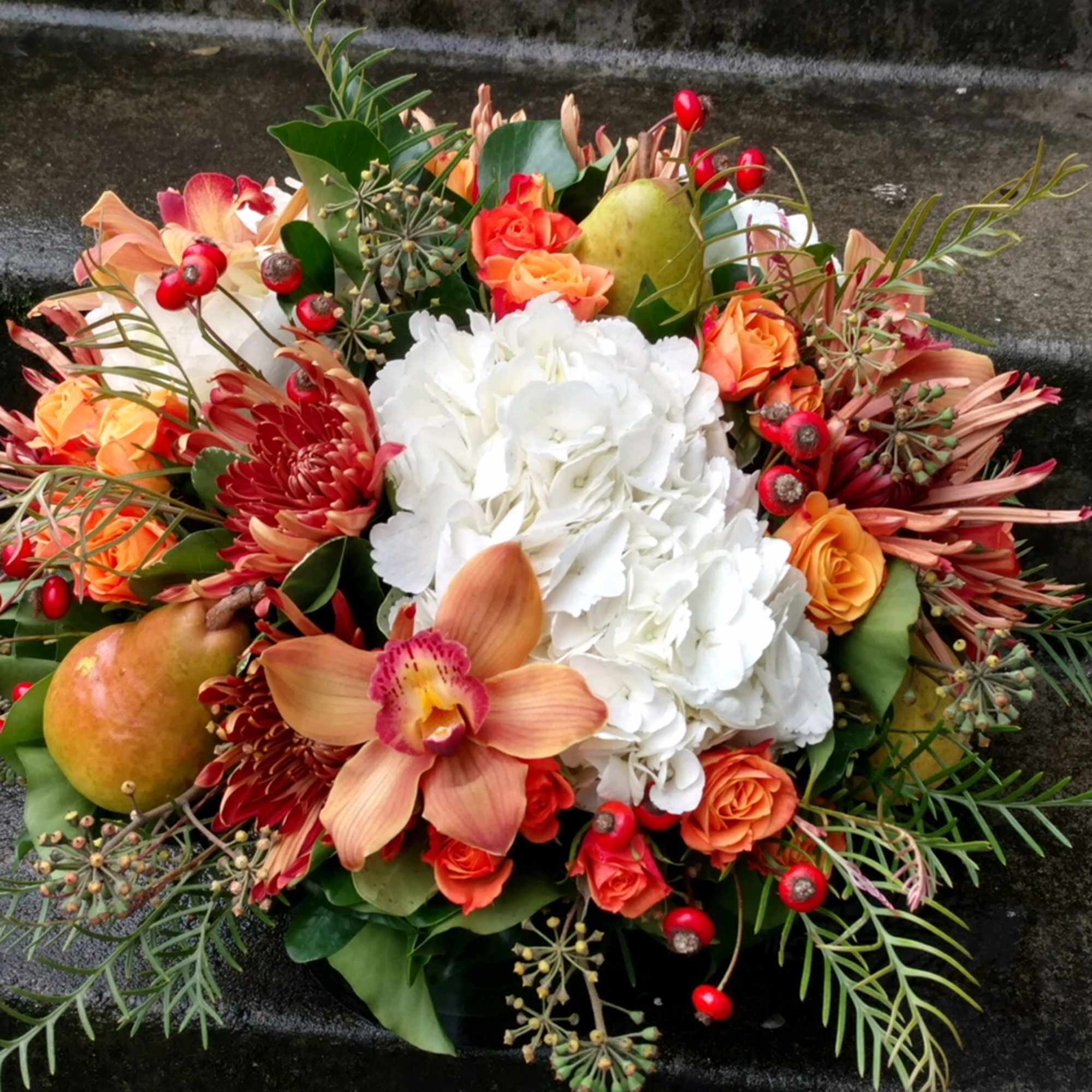 Mixed bouquet with white hydrangea, orange roses, and an orchid