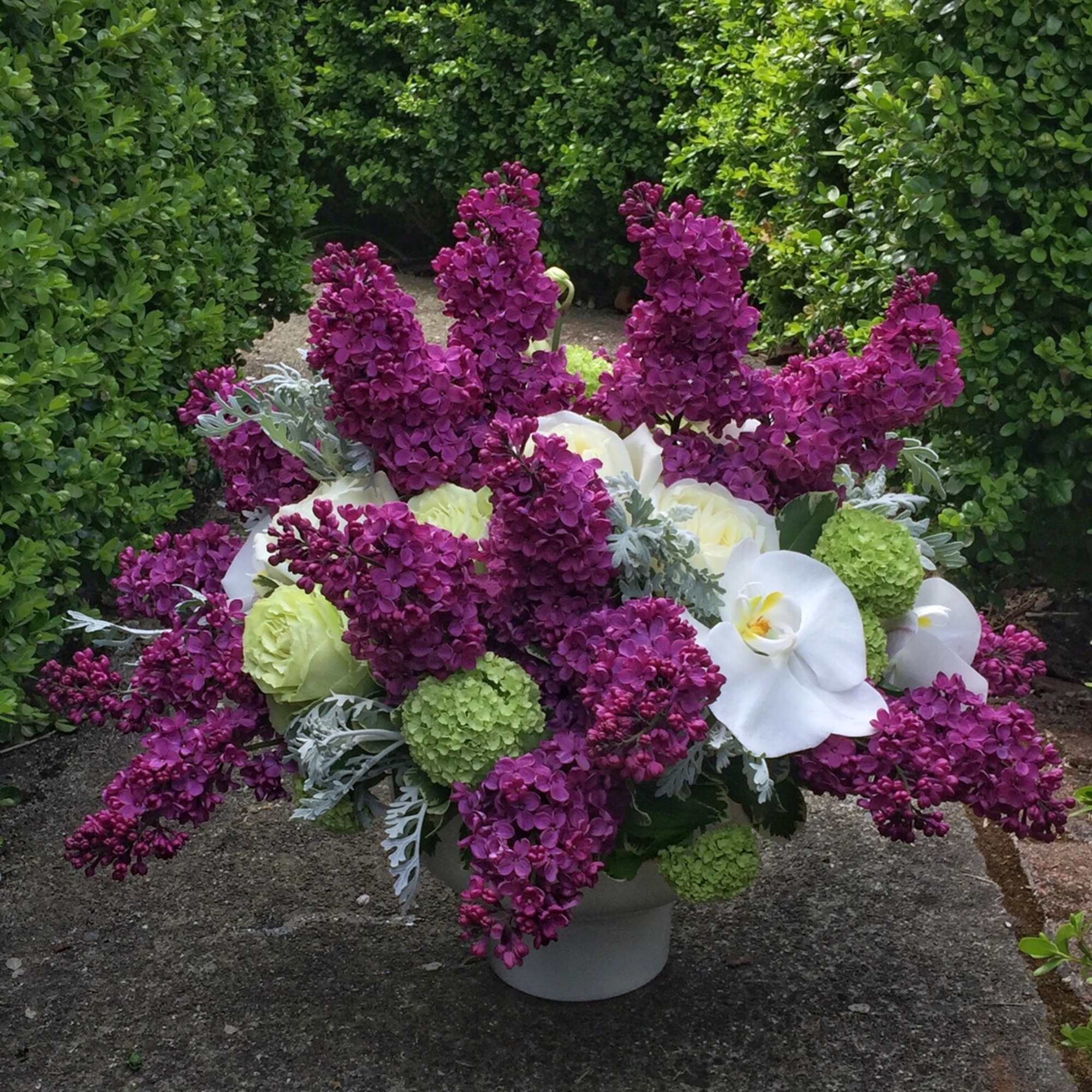Purple and white floral arrangement in a white vase
