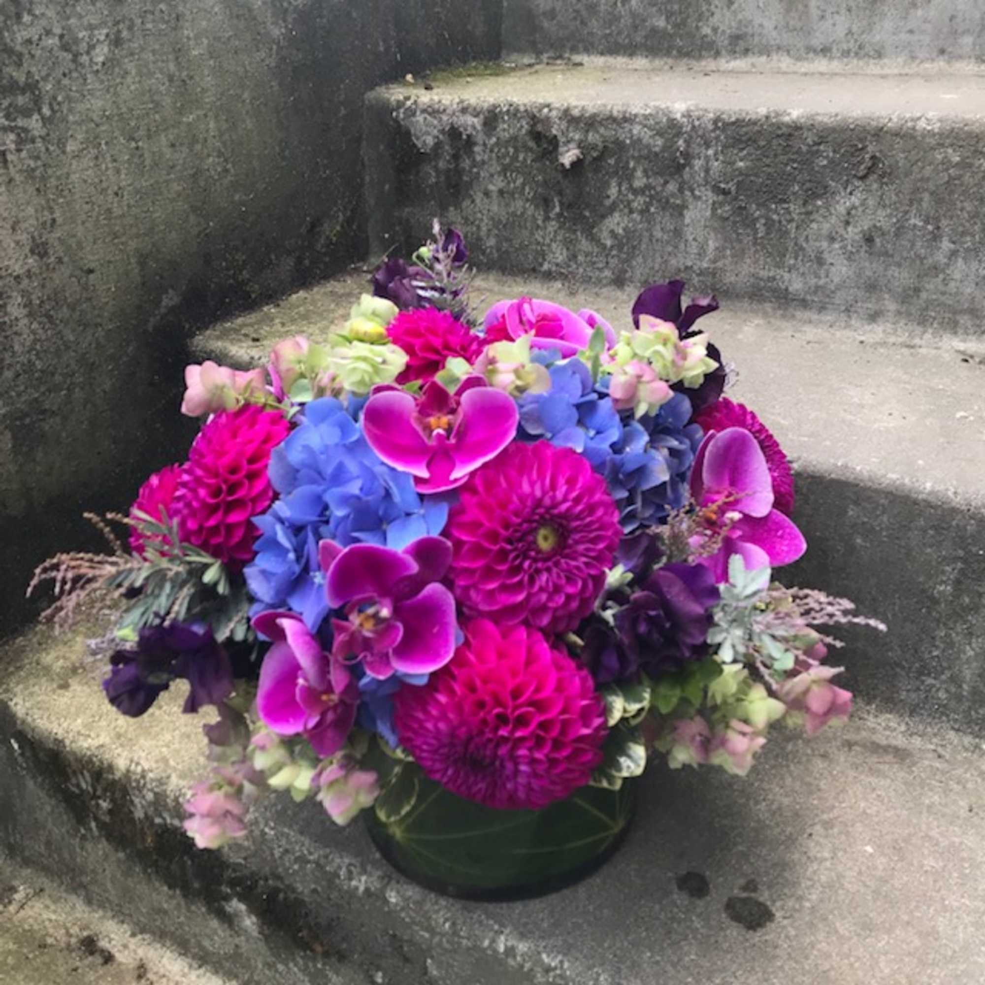 Bright bouquet of pink, purple, and blue flowers in a low container