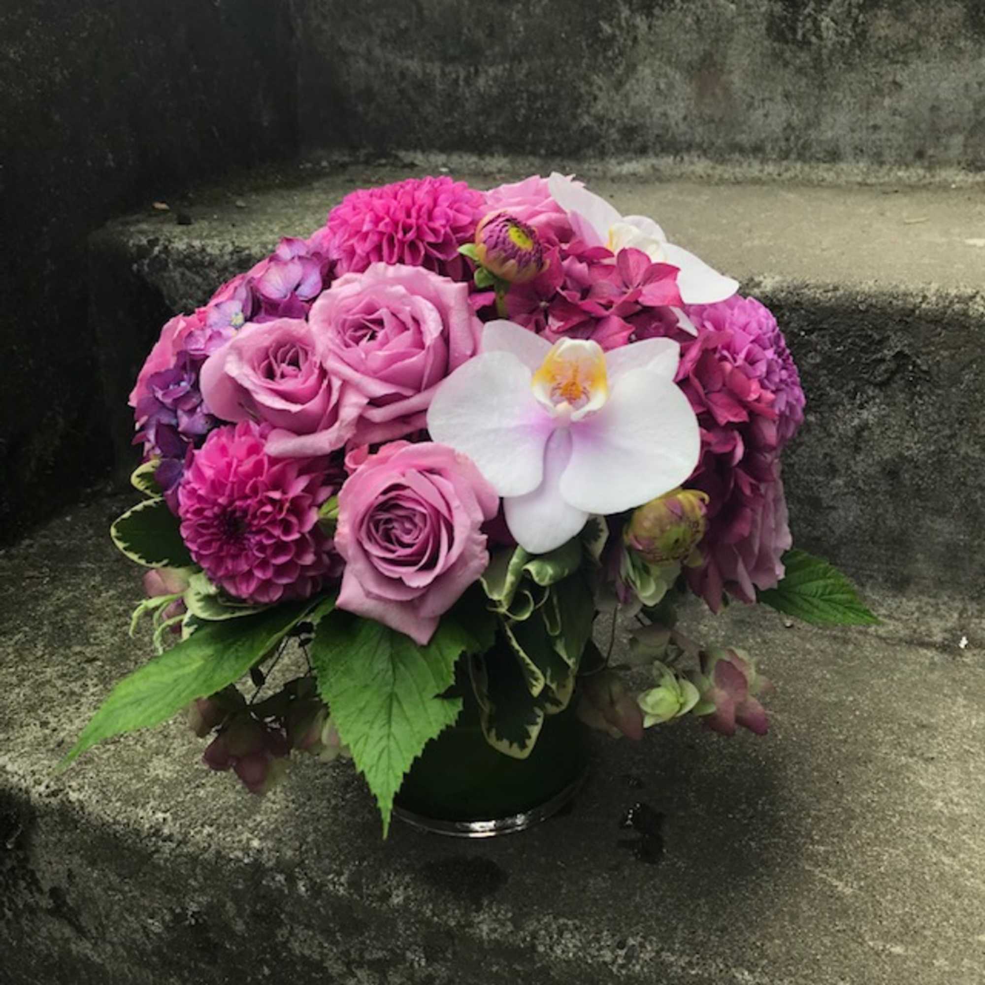 Pink roses and orchids arranged in a low vase
