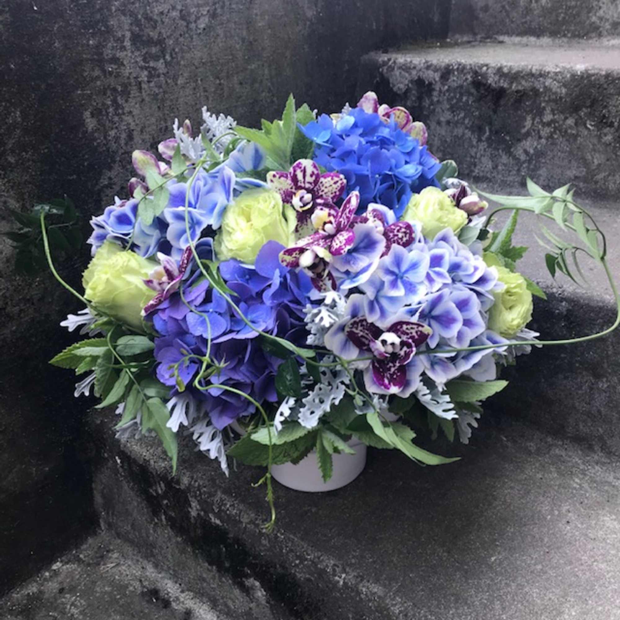 Blue and purple floral arrangement in a white container