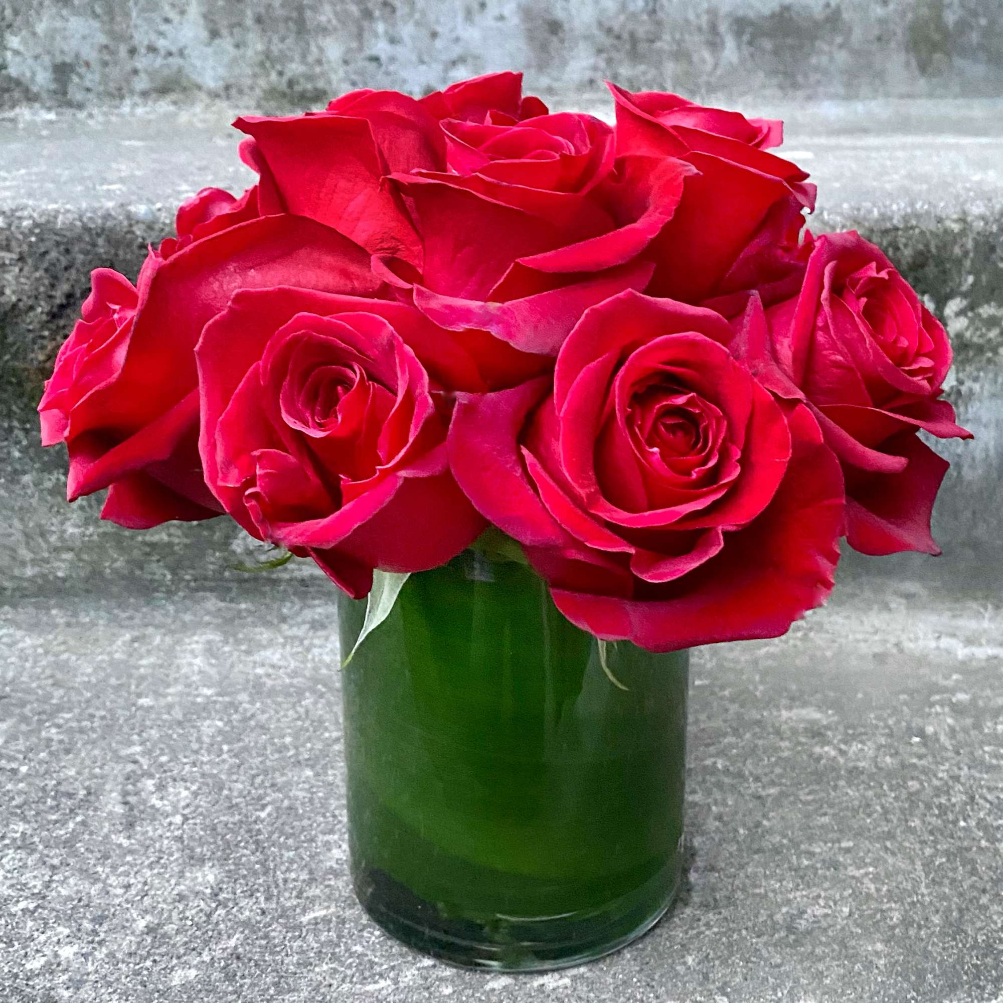 Red roses arranged in a green glass vase